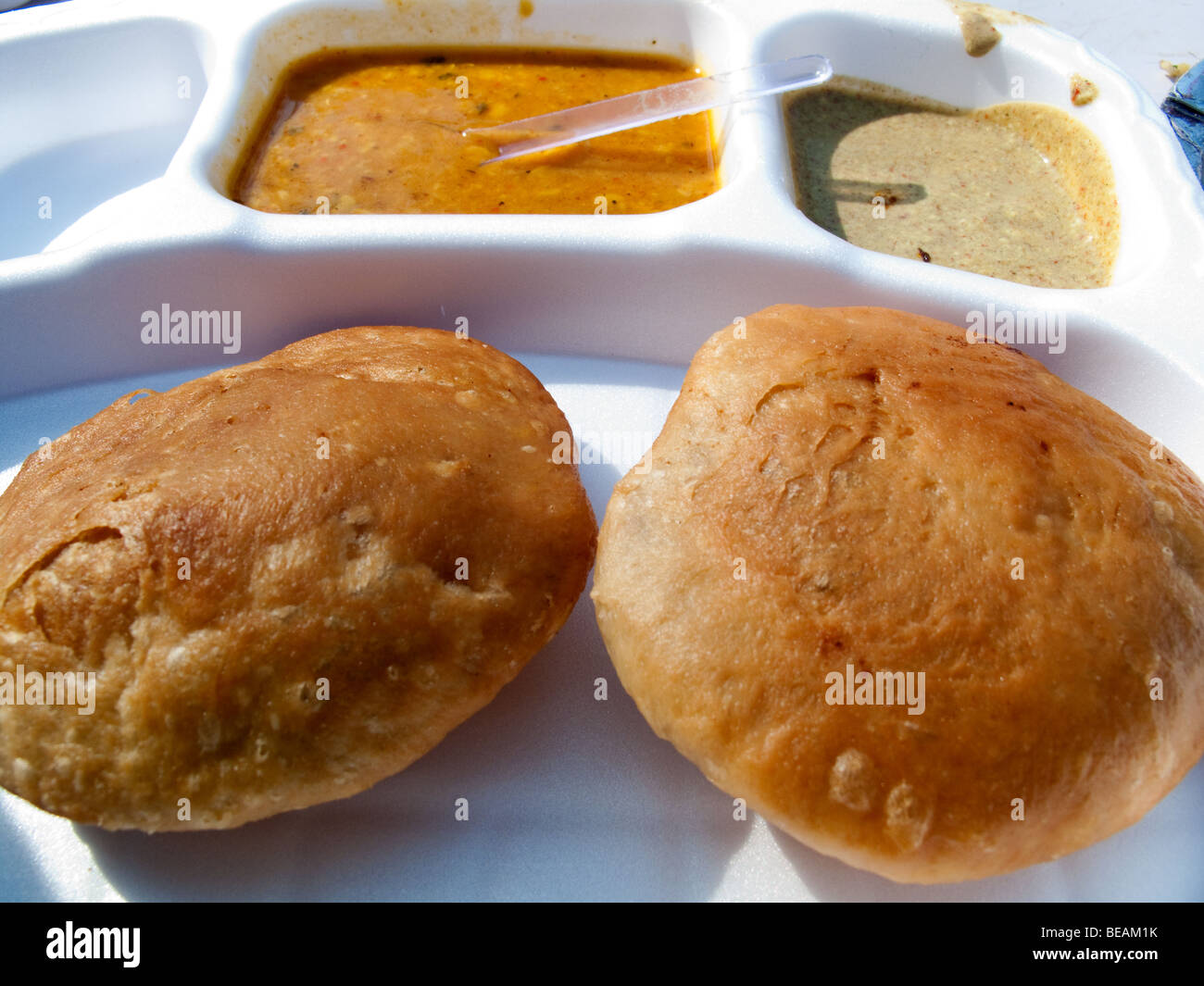 Il cibo indiano elementi su un piatto di plastica bianca. Questi sono kachoris morbido con una patata oleoso curry, perfetto come uno spuntino veloce. Foto Stock