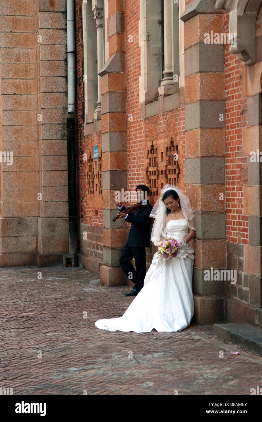 Vietnamita serenate uomo la sua sposa tenendo i loro pre-wedding shoot presso la cattedrale di Notre Dame a Ho Chi Minh City, Vietnam Foto Stock