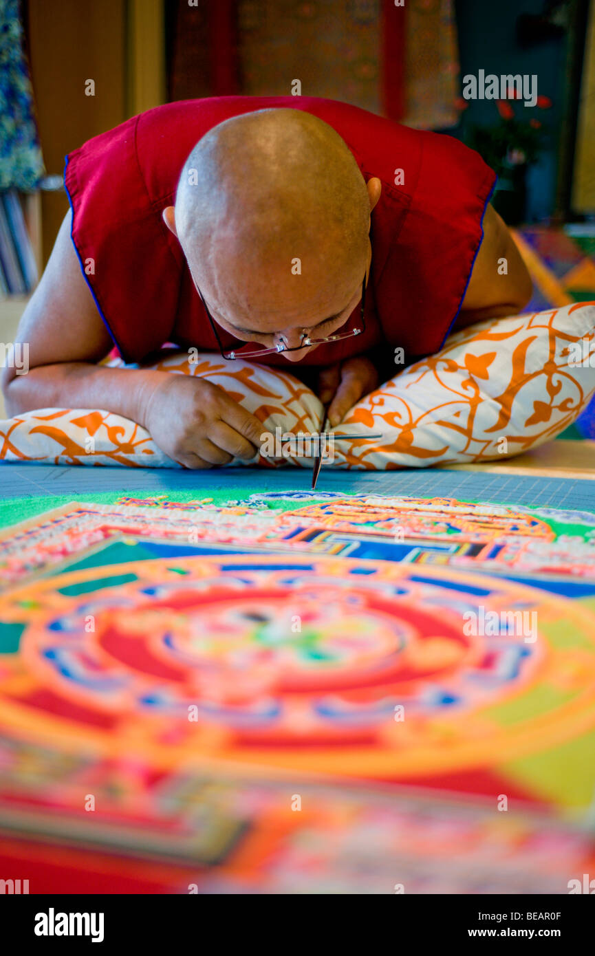 Monaco tibetano VenoDhondup Tsering opere attentamente su un coloratissimo Mandala di sabbia in Ruidoso, Nuovo Messico. Foto Stock