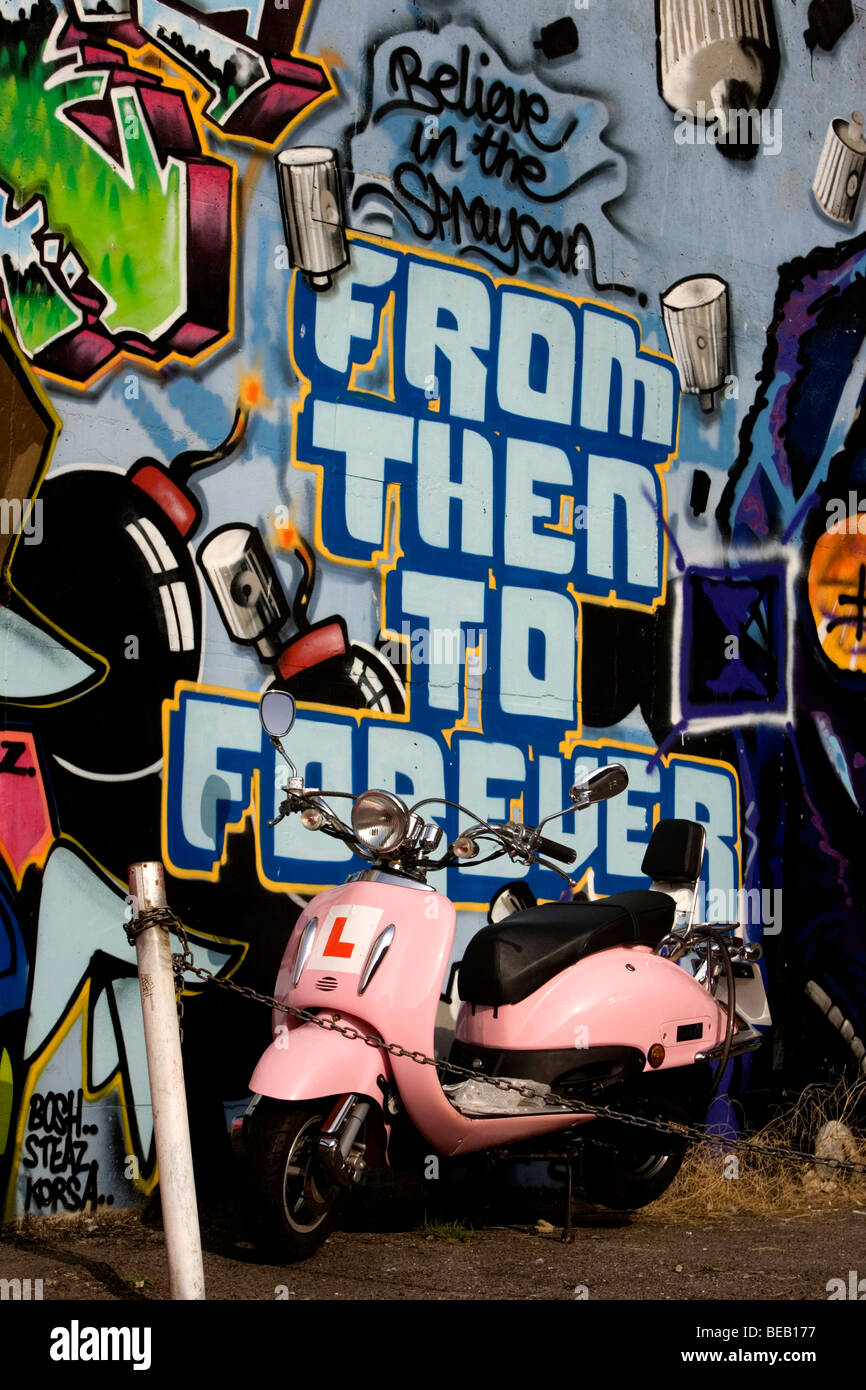 Graffiti nella foto dietro un parcheggiato retrò stile Vespa scooter nelle stradine della Brighton, East Sussex, Regno Unito. Foto Stock