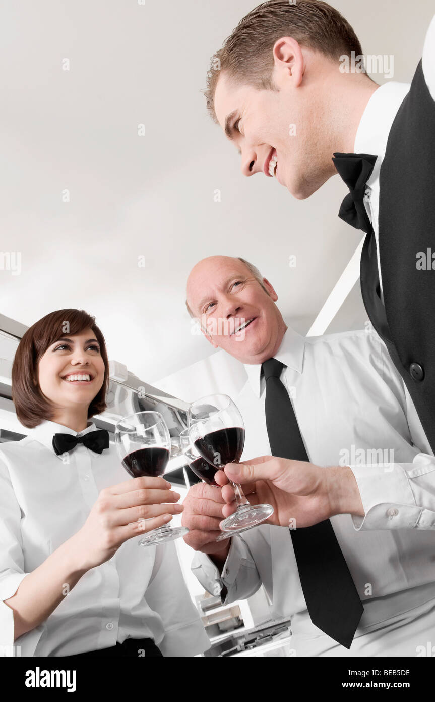 Due uomini e una donna tostare con il vino Foto Stock