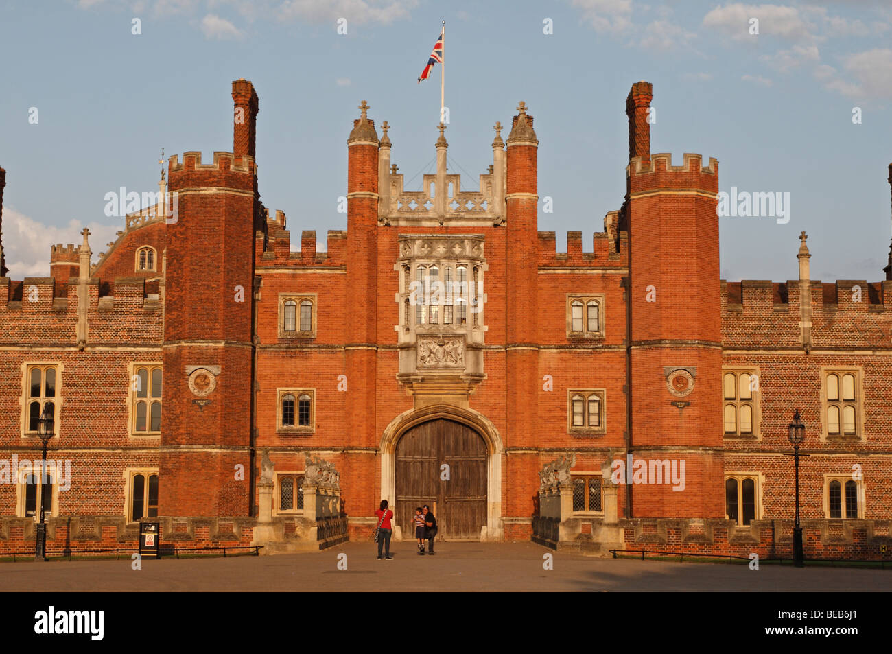 Una madre fotografie della sua famiglia di fronte all'ingresso principale dell'Hampton Court Palace, Surrey, Regno Unito su una bella sera d'estate. Foto Stock