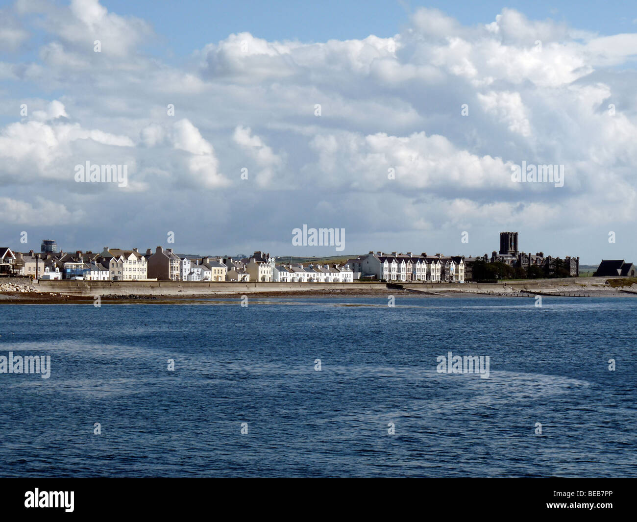 Guardando attraverso una baia blu verso il villaggio costiero di Derbyhaven contro uno sfondo di soffici nuvole cumulus Foto Stock