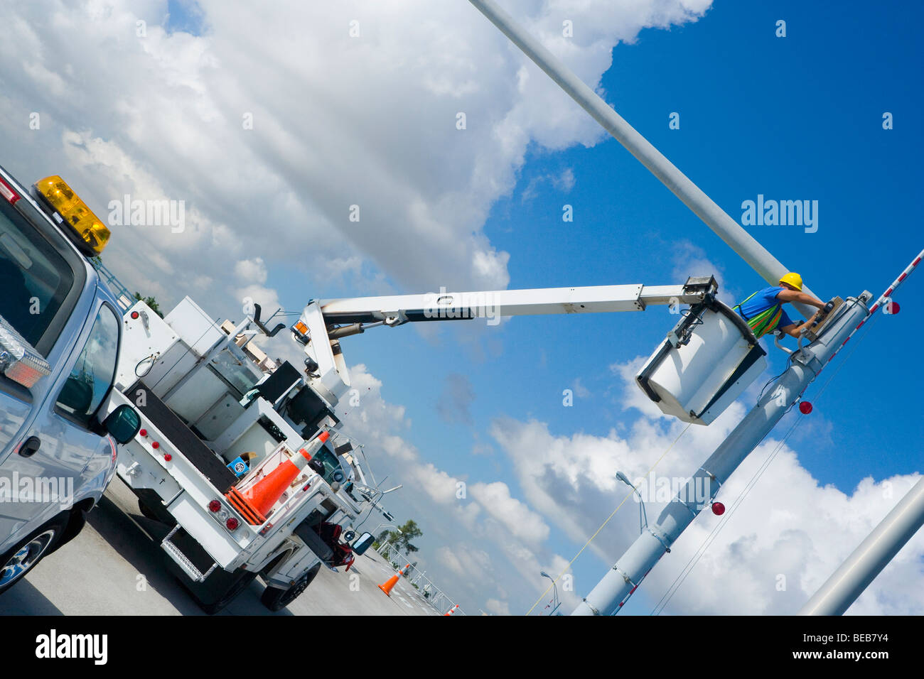 Basso angolo di vista di un tecnico di manutenzione su una gru mobile la riparazione di una videocamera di sicurezza su un palo Foto Stock