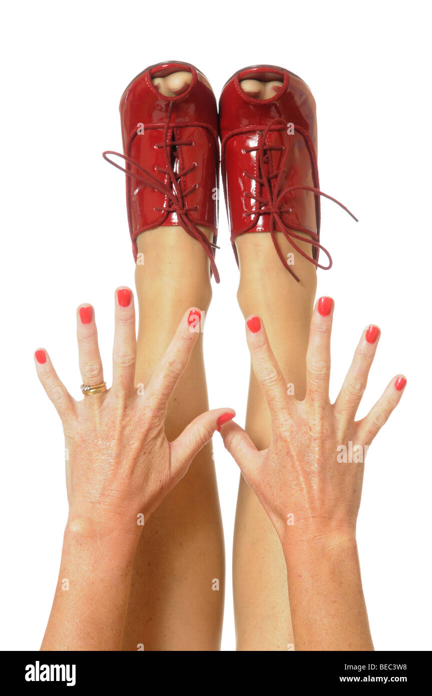 Dipinto di rosso le unghie delle dita di mani tese al rosso alta scarpe con tacco Foto Stock