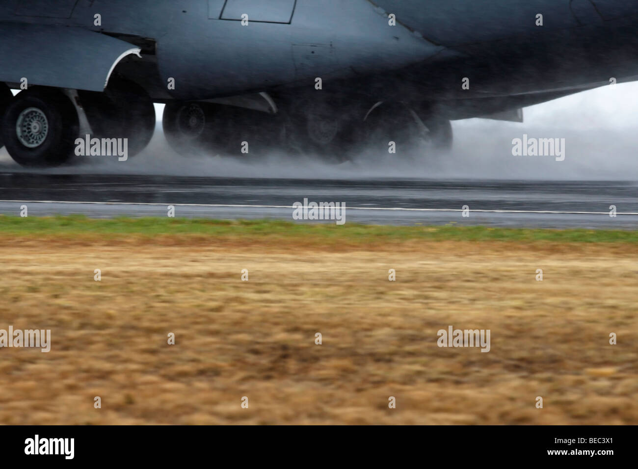 Sotto il carrello di un C-17 Globemaster III Trasporti aerei di atterraggio su una pista bagnata Foto Stock