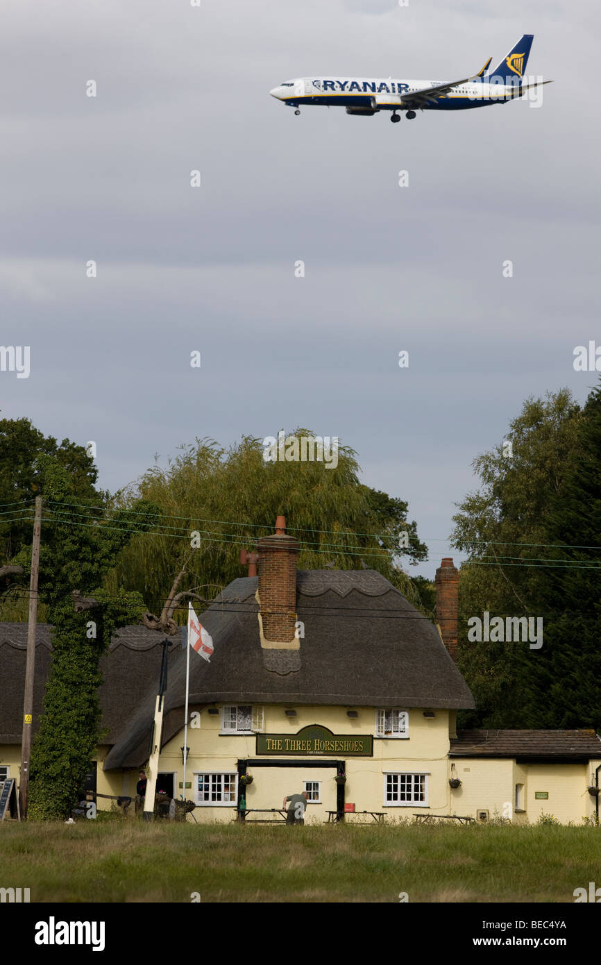 Un passeggero Ryanair jet al di sopra delle tre ferri di cavallo in pub Molehill verde, Essex, sul suo modo di terra presso l'aeroporto di Stansted Foto Stock