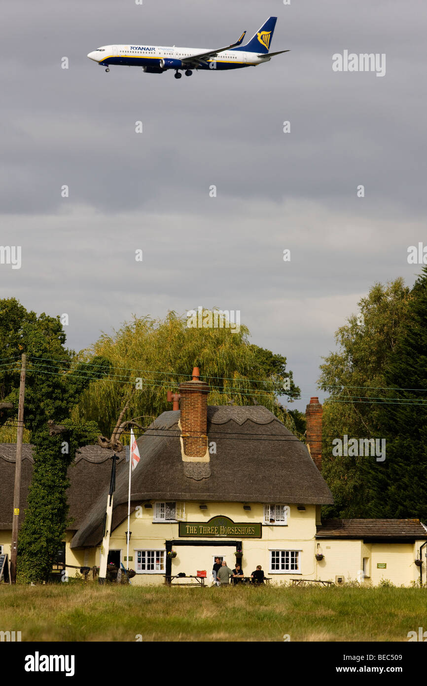 Un passeggero Ryanair jet al di sopra delle tre ferri di cavallo in pub Molehill verde, Essex, sul suo modo di terra presso l'aeroporto di Stansted Foto Stock
