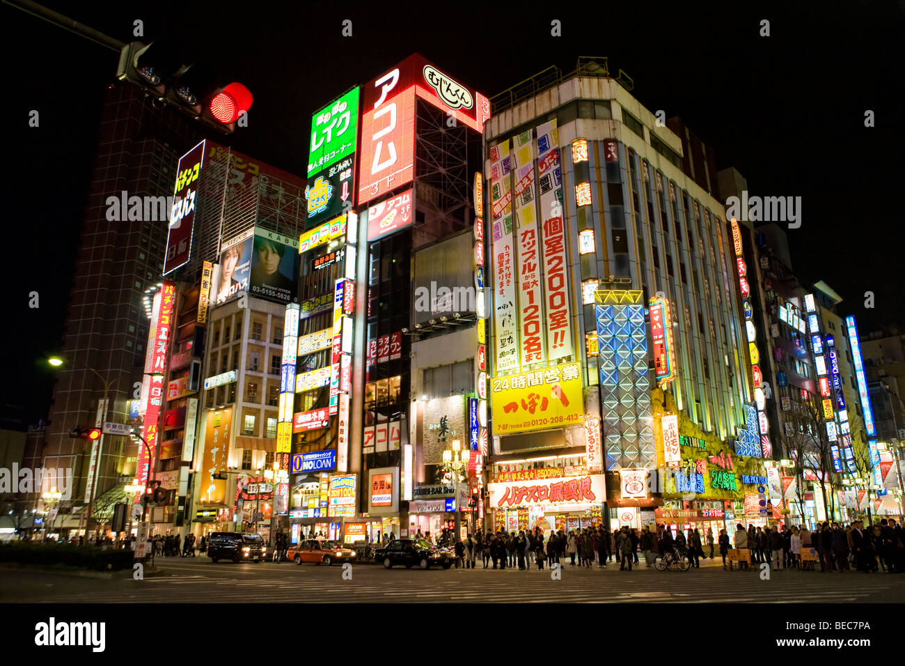 La folla attraversando la strada in corrispondenza di un incrocio occupato in notturna a Shinjuku, Tokyo Foto Stock