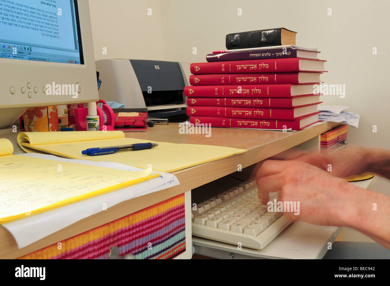 Copy-Editor femmina lavorando davanti a un computer la modifica di un documento accademico con l aiuto di un dizionario e altri libri di testo Foto Stock