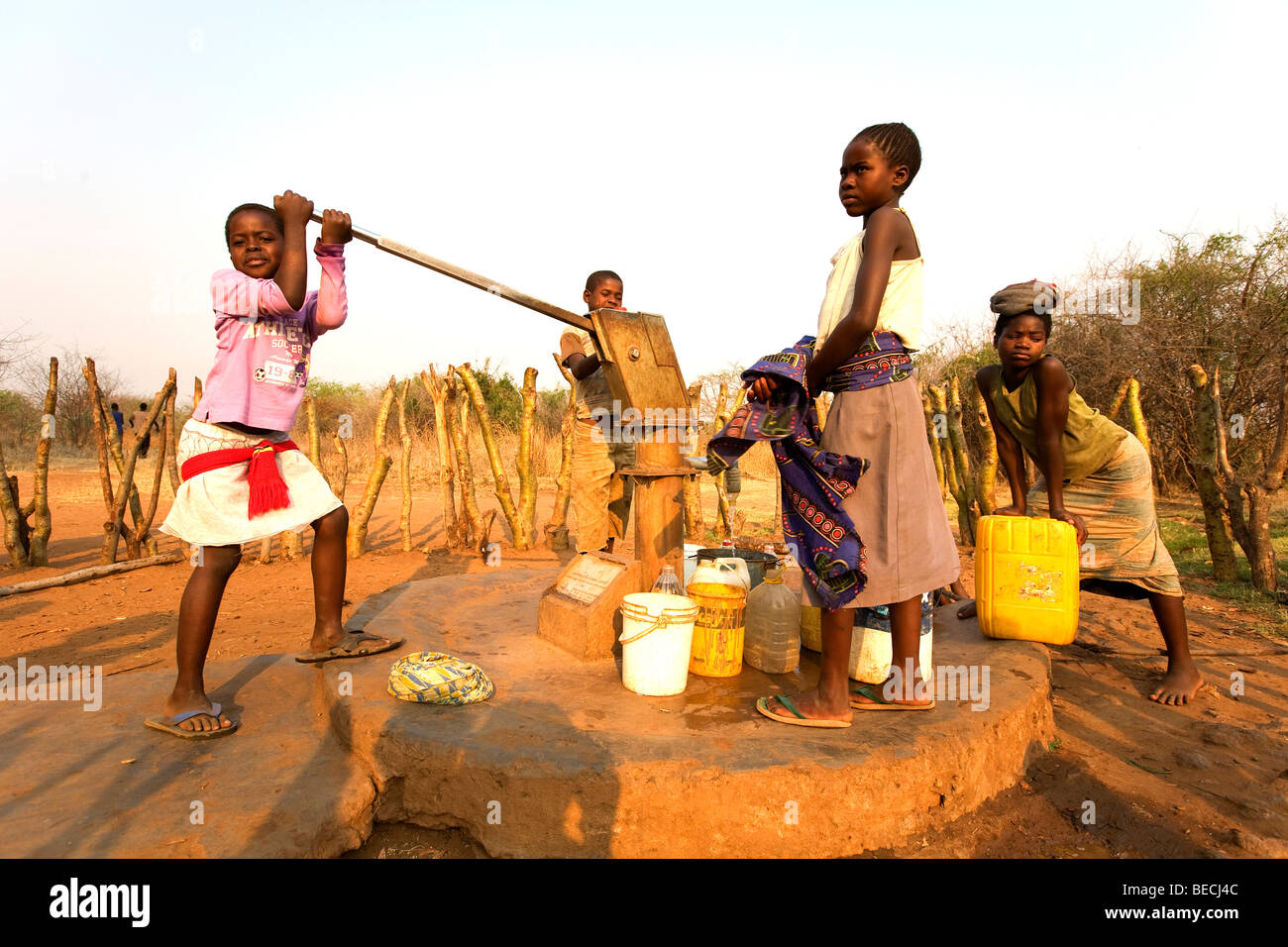 Bambini il pompaggio di acqua al di fuori di un bene, villaggio africano Sambona, sud della provincia, la Repubblica di Zambia e Africa Foto Stock