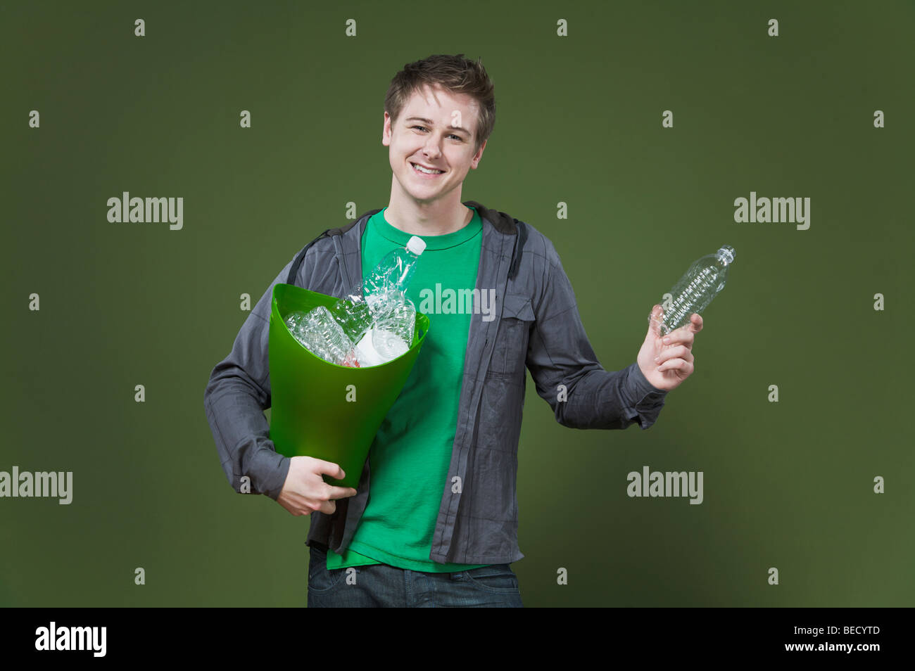 Ritratto di un uomo con un contenitore di riciclaggio e sorridente Foto Stock