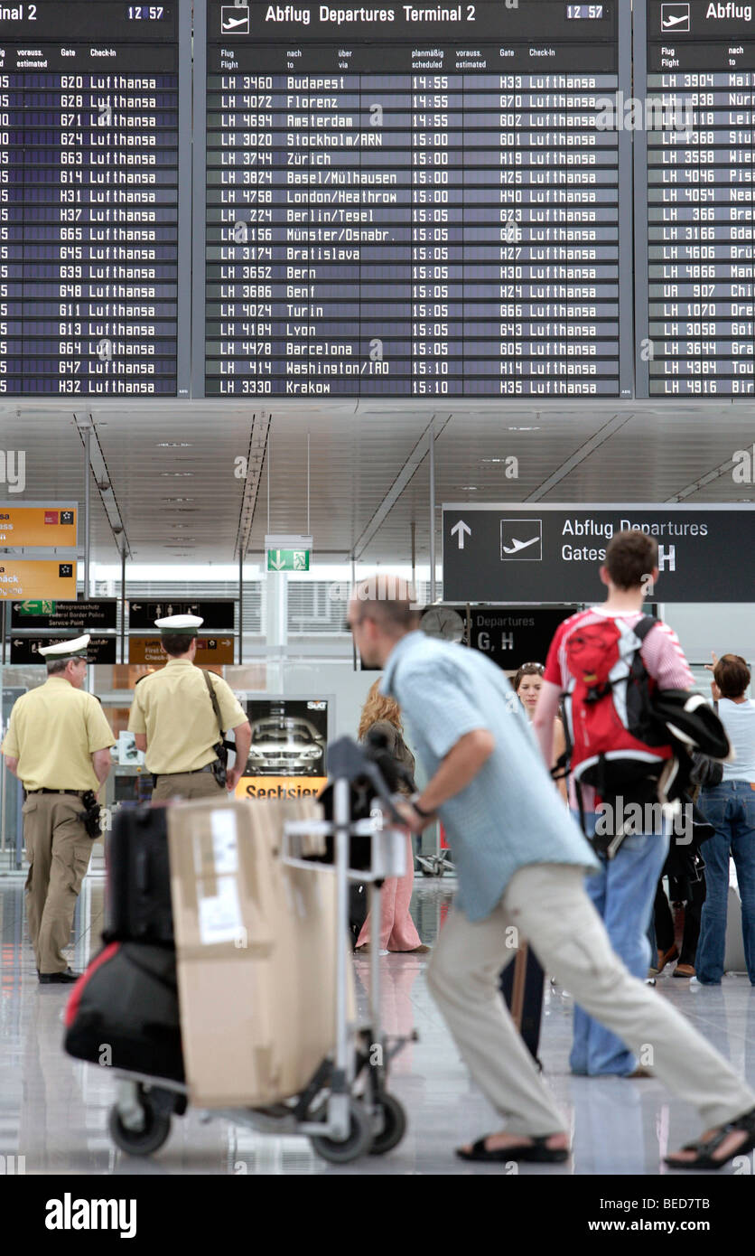 I passeggeri nella parte anteriore della scheda informazioni elencando gli orari di partenza, il Terminal 2 dell'aeroporto di Monaco Franz-Josef-Strauss aria Foto Stock