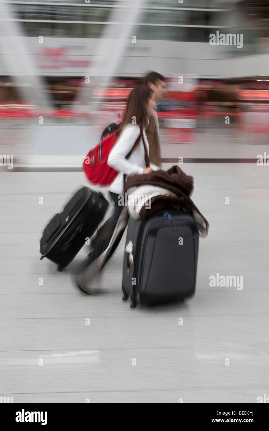 Immagine sfocata, giovane coppia rapidamente a piedi con i bagagli nella sala partenze presso l'aeroporto di Dusseldorf, Duesseldorf Nord Reno Foto Stock