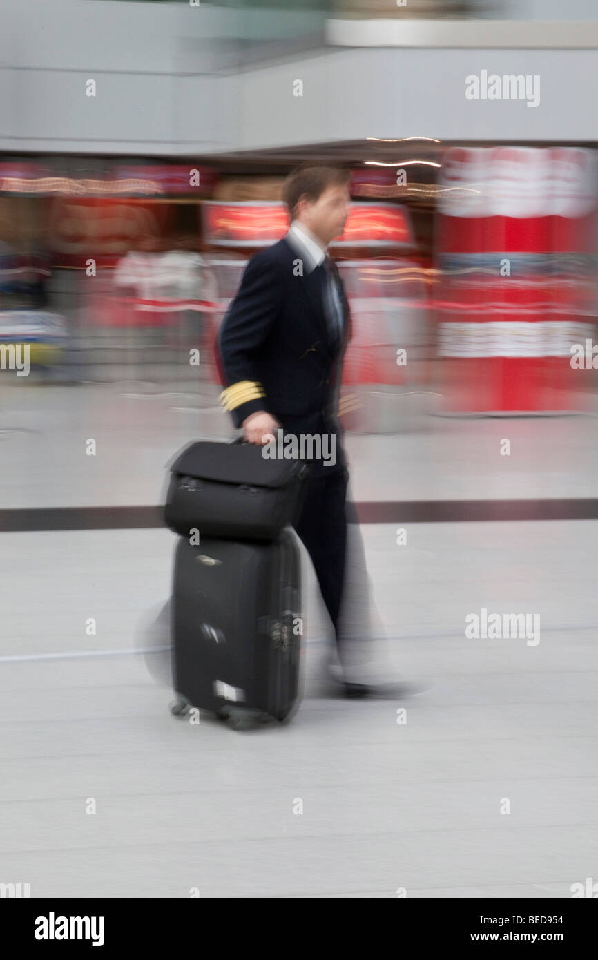 Immagine sfocata, Lufthansa dipendente rapidamente a piedi con i bagagli nella sala partenze presso l'aeroporto di Dusseldorf, Duesseldorf, Nord Foto Stock