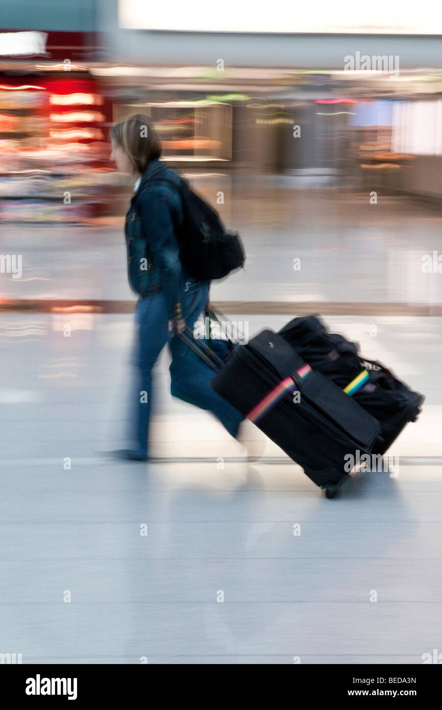 Immagine sfocata, donna tirando rapidamente i suoi bagagli dietro di lei nella sala partenze presso l'aeroporto di Dusseldorf, Duesseldorf Nord Rh Foto Stock