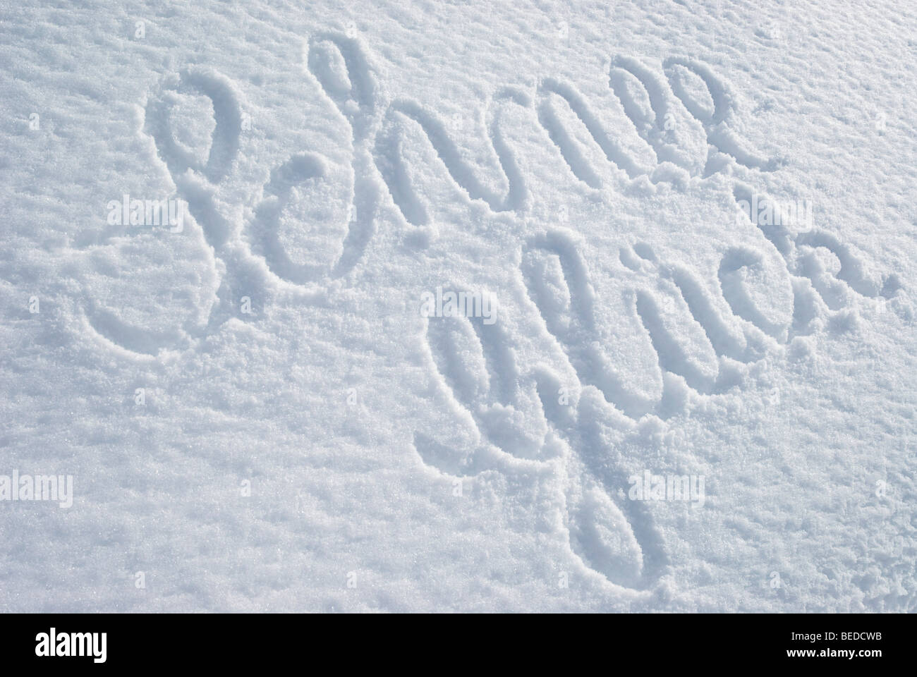 La parola Schnee-Glueck, felicità della neve, scritta su una coperta di neve intatta Foto Stock