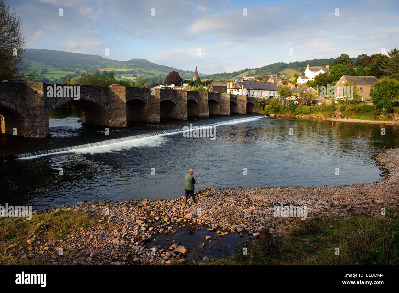 Il vecchio ponte sul fiume Usk a Crickhowell, Powys Mid Wales UK, con Table Mountain a distanza, e un uomo la pesca Foto Stock