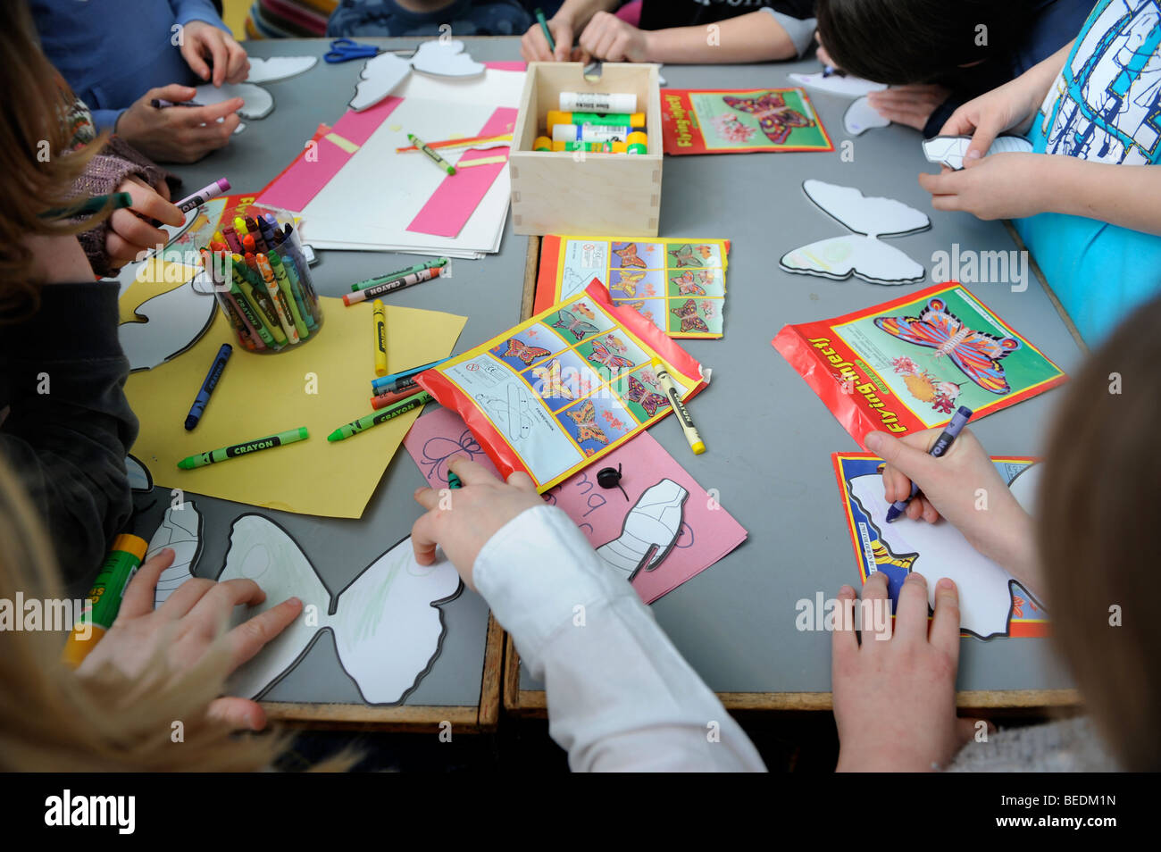Bambini disegno a tagliare le farfalle in una Domenica scuola REGNO UNITO Foto Stock