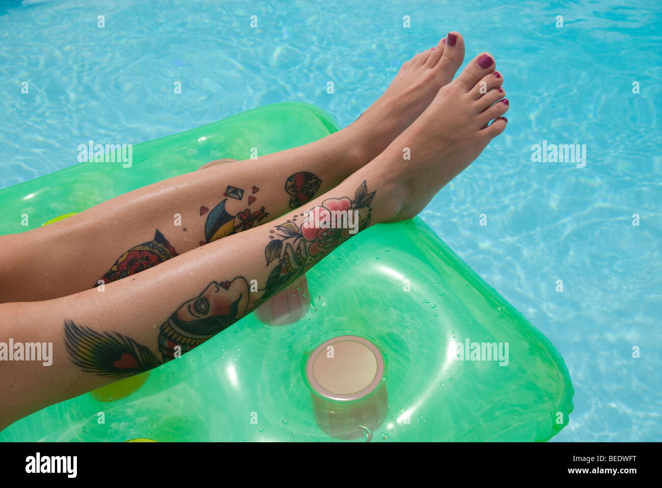 Tattoo'd gambe su un lilo Foto Stock