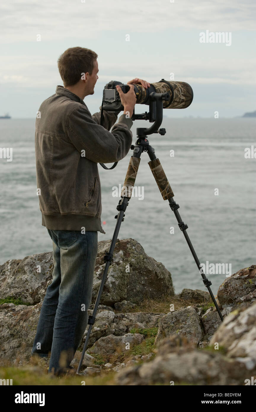 Natura fotografo Peter Moonlight usando un super teleobiettivo e una reflex digitale (DSLR) sulla costa gallese. Foto Stock