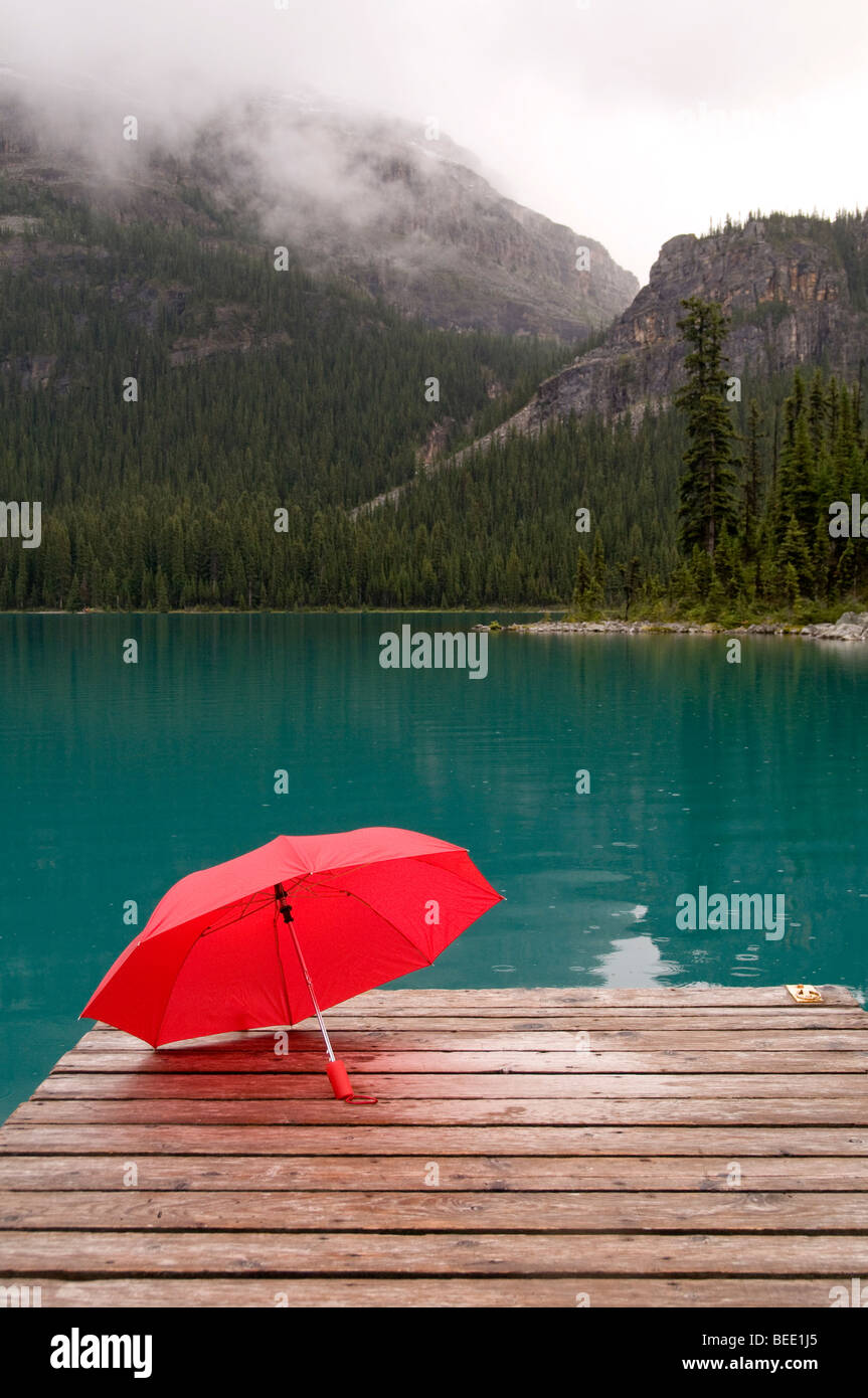 Ombrellone rosso con il lago di smeraldo acqua e dock Foto Stock