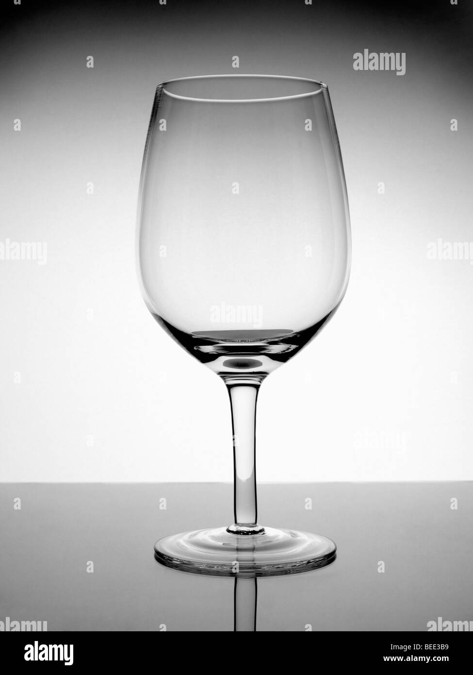 Un colpo di un vuoto di bicchiere di vino con la riflessione su sfondo bianco. Foto Stock