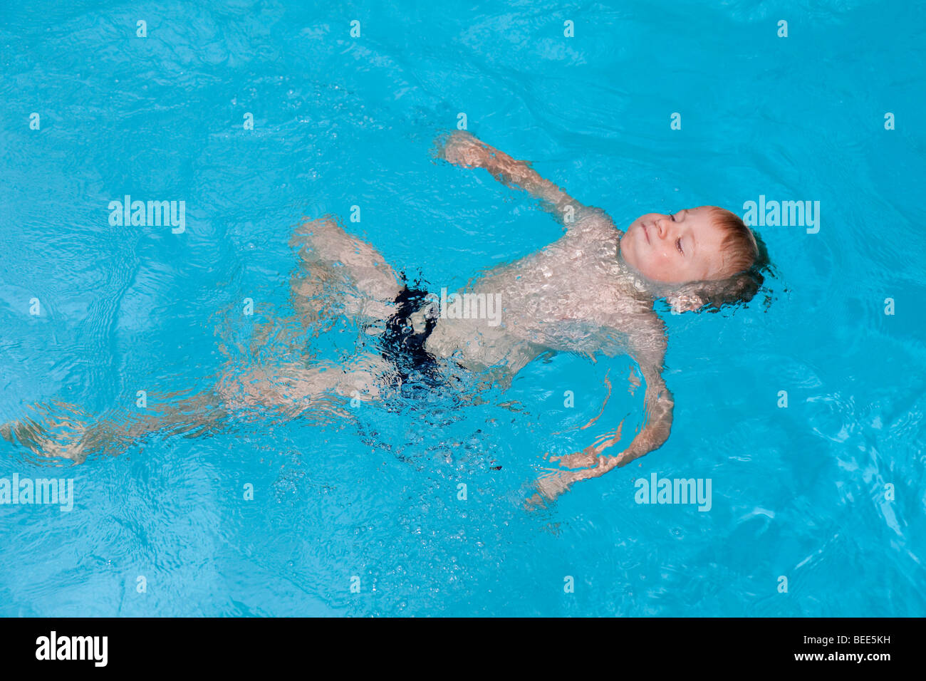 Ragazzo di 5 anni nuoto il dorso in una piscina Foto Stock