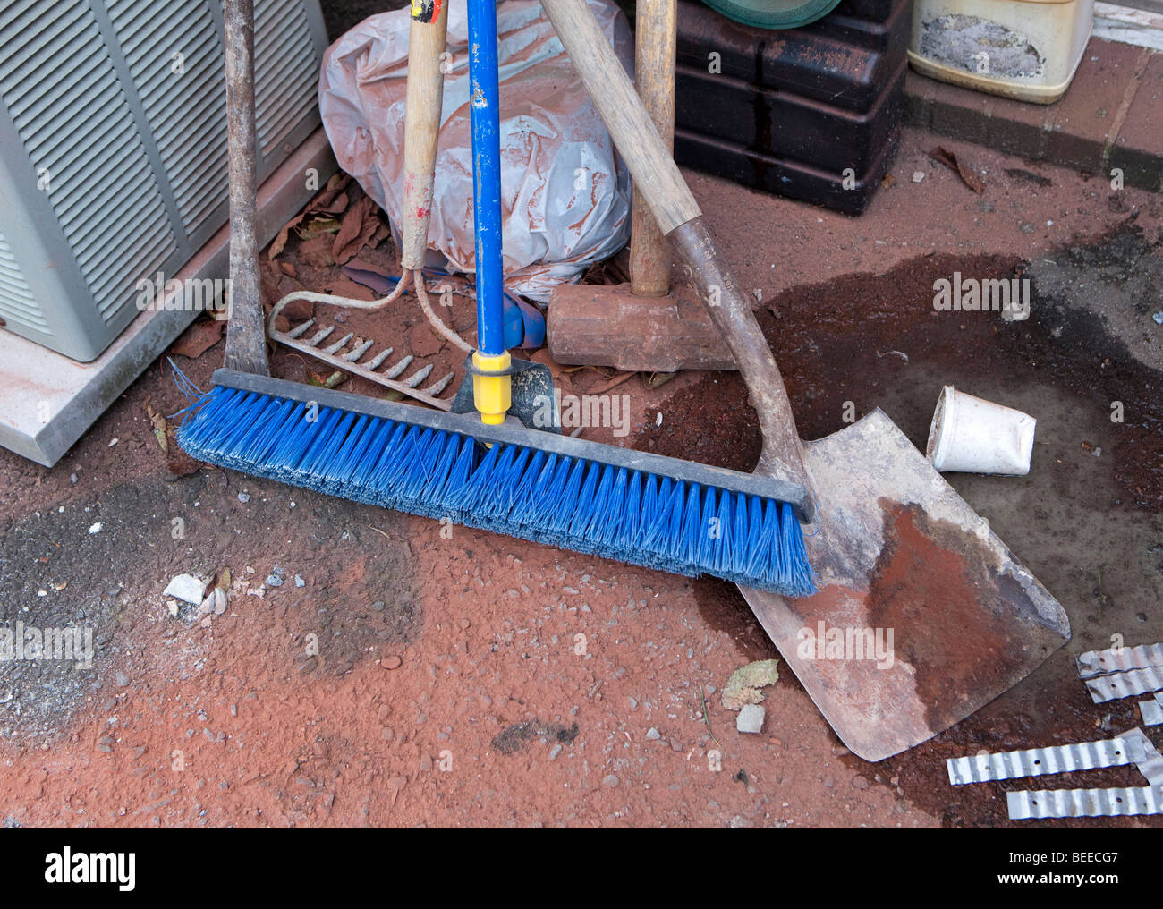 Un nylon blu scopa una pala di un palanchino una mazza un rastrello in corrispondenza di un sito in costruzione. Foto Stock