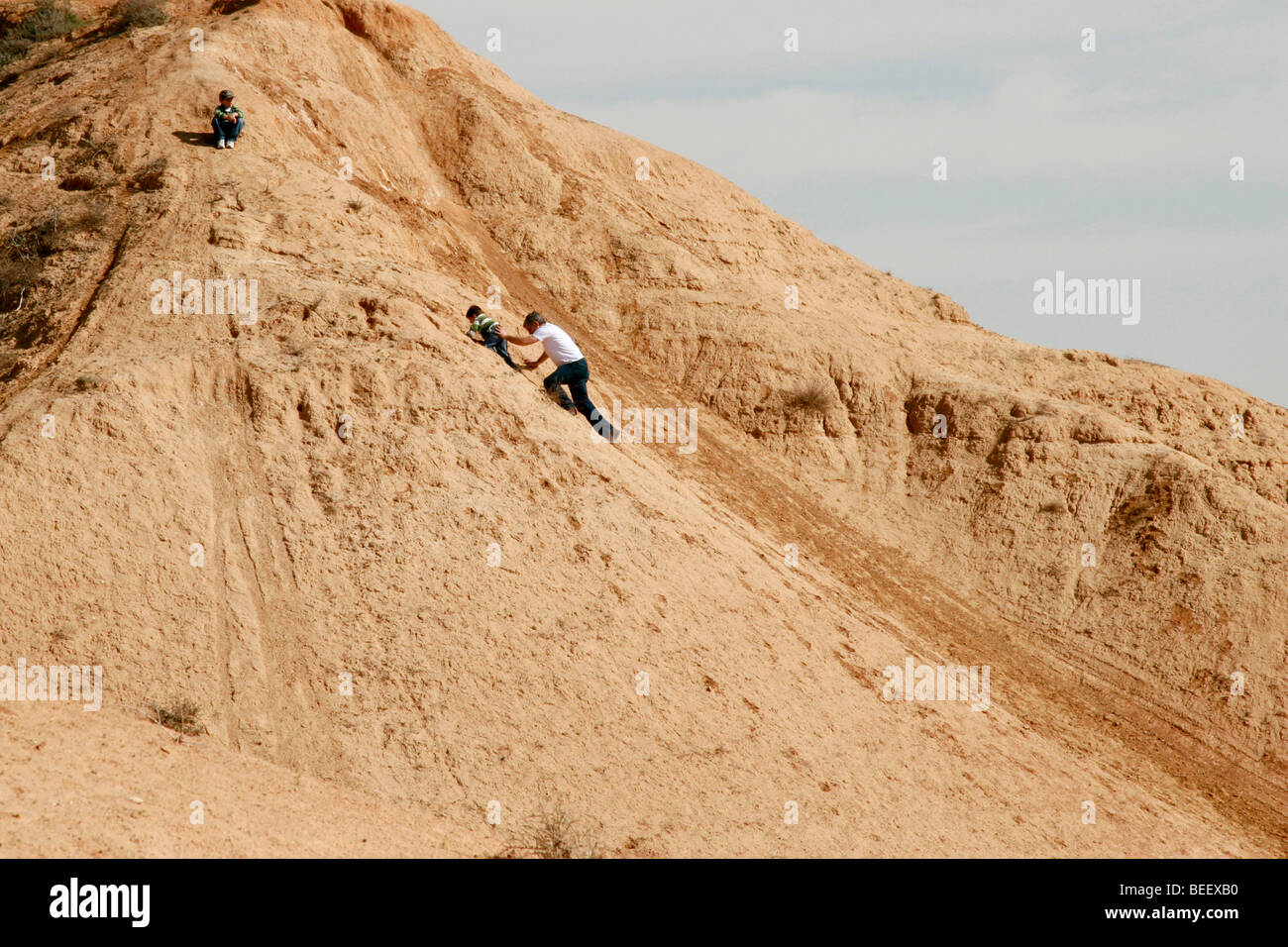 Israele Negev pianure, Nitzana padre aiuta il bambino strisciare su di una duna di sabbia Foto Stock
