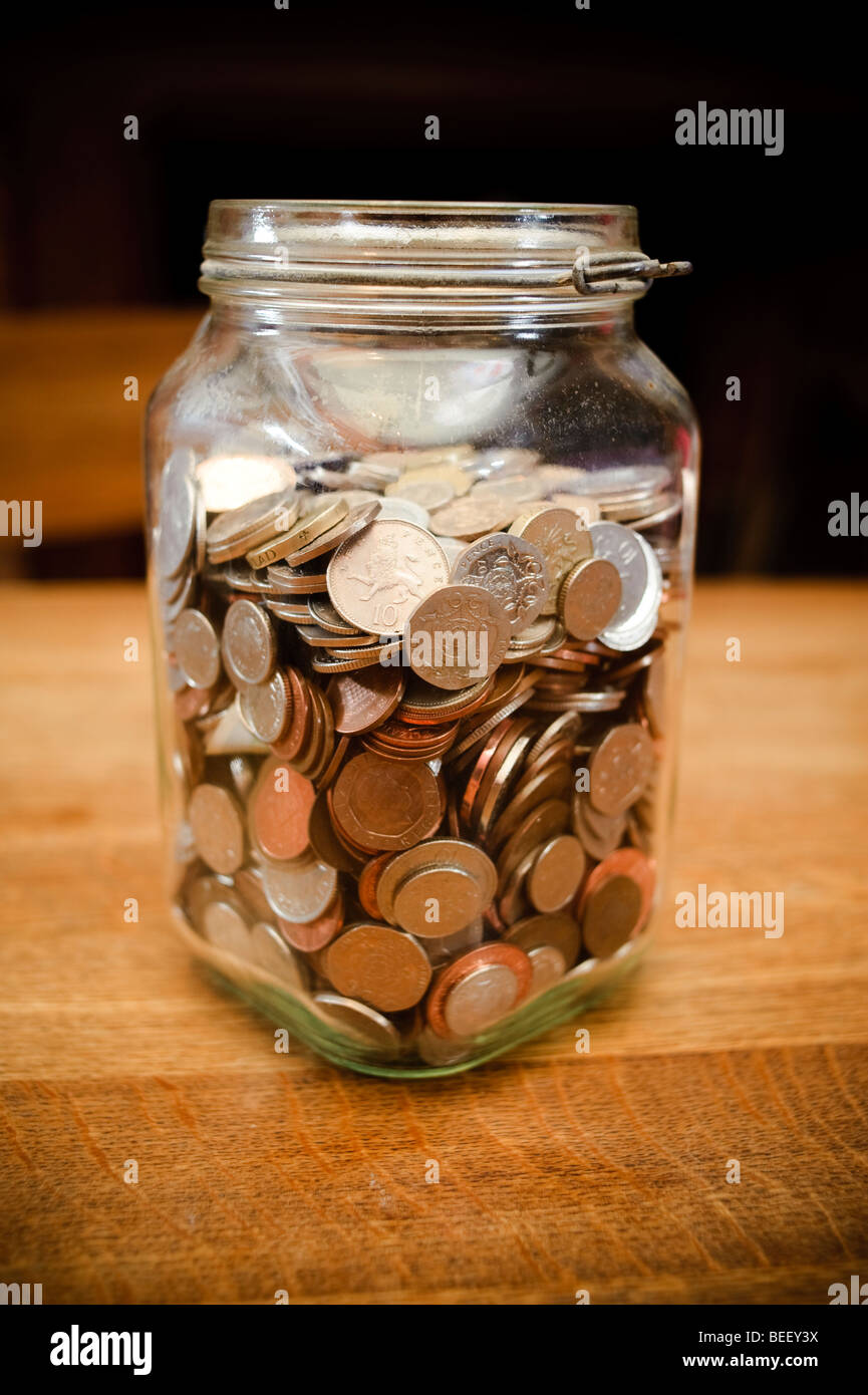 Inceppamento in vetro vaso pieno del British English UK bronzo e monete d'argento - risparmi soldi contanti "Rainy day fondo" Foto Stock