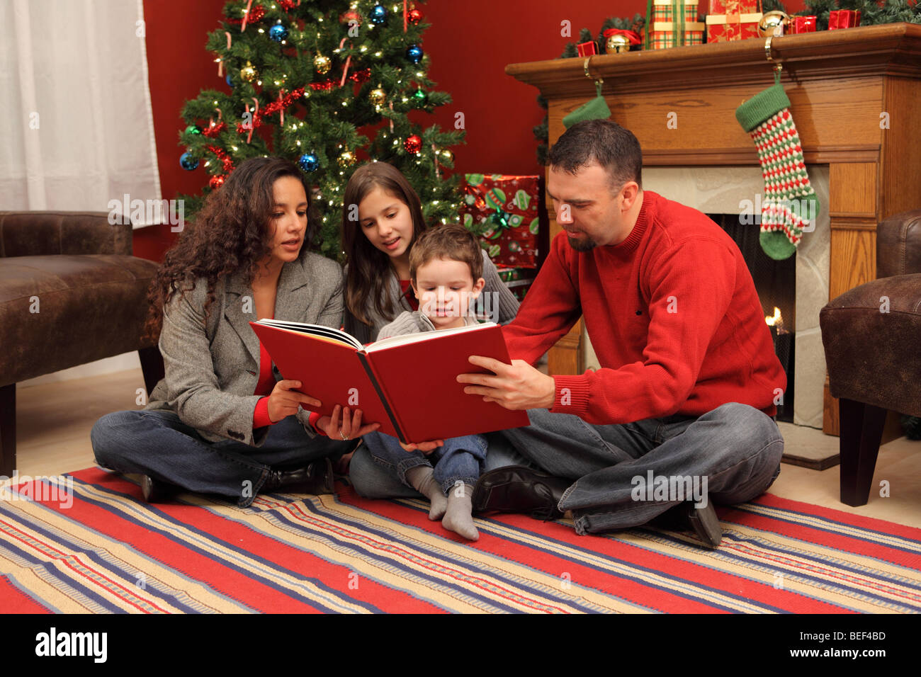 La famiglia la lettura del libro di Natale insieme Foto Stock