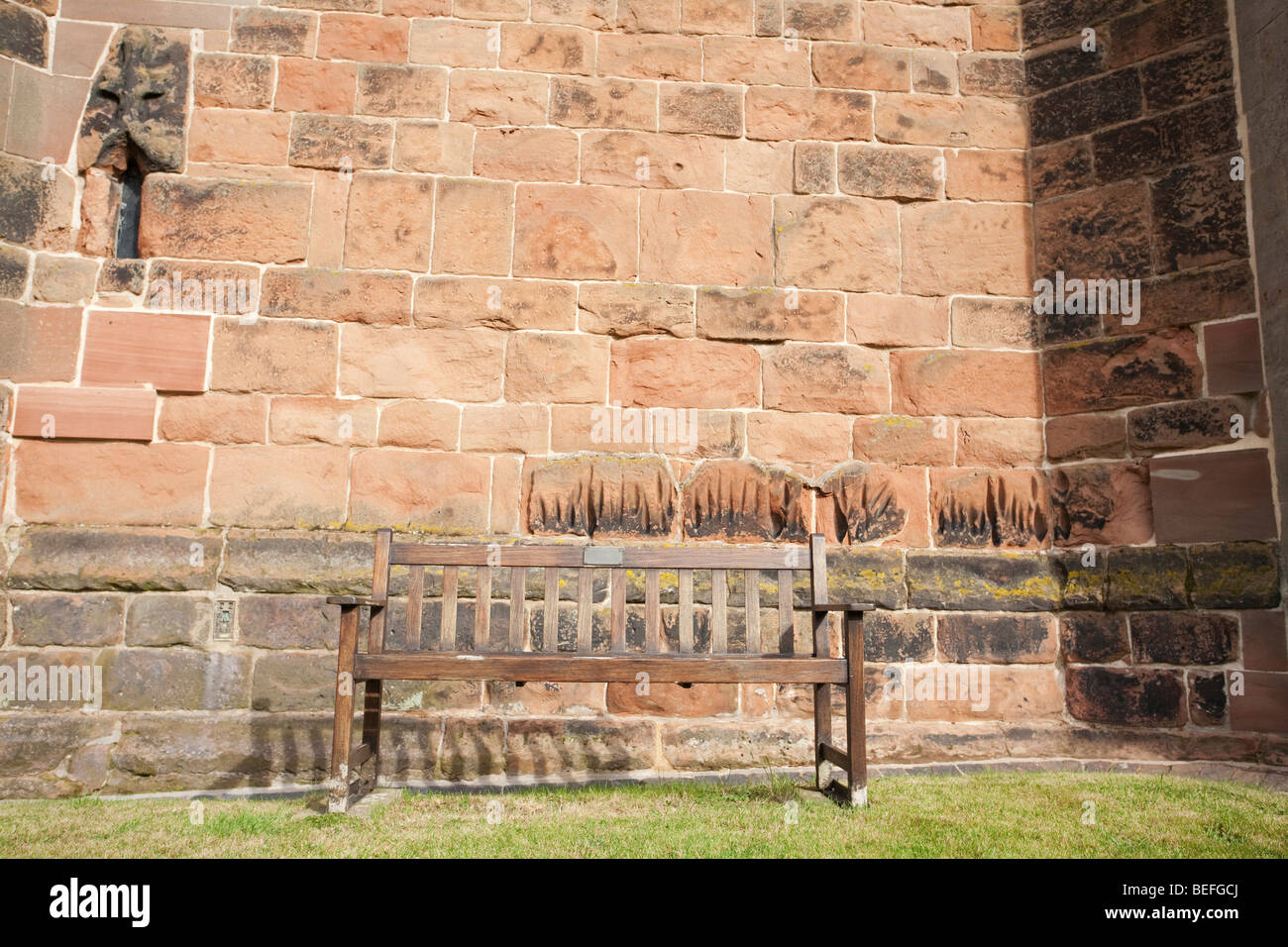 Sedile unico sul prato di fronte ad una parete della chiesa Foto Stock