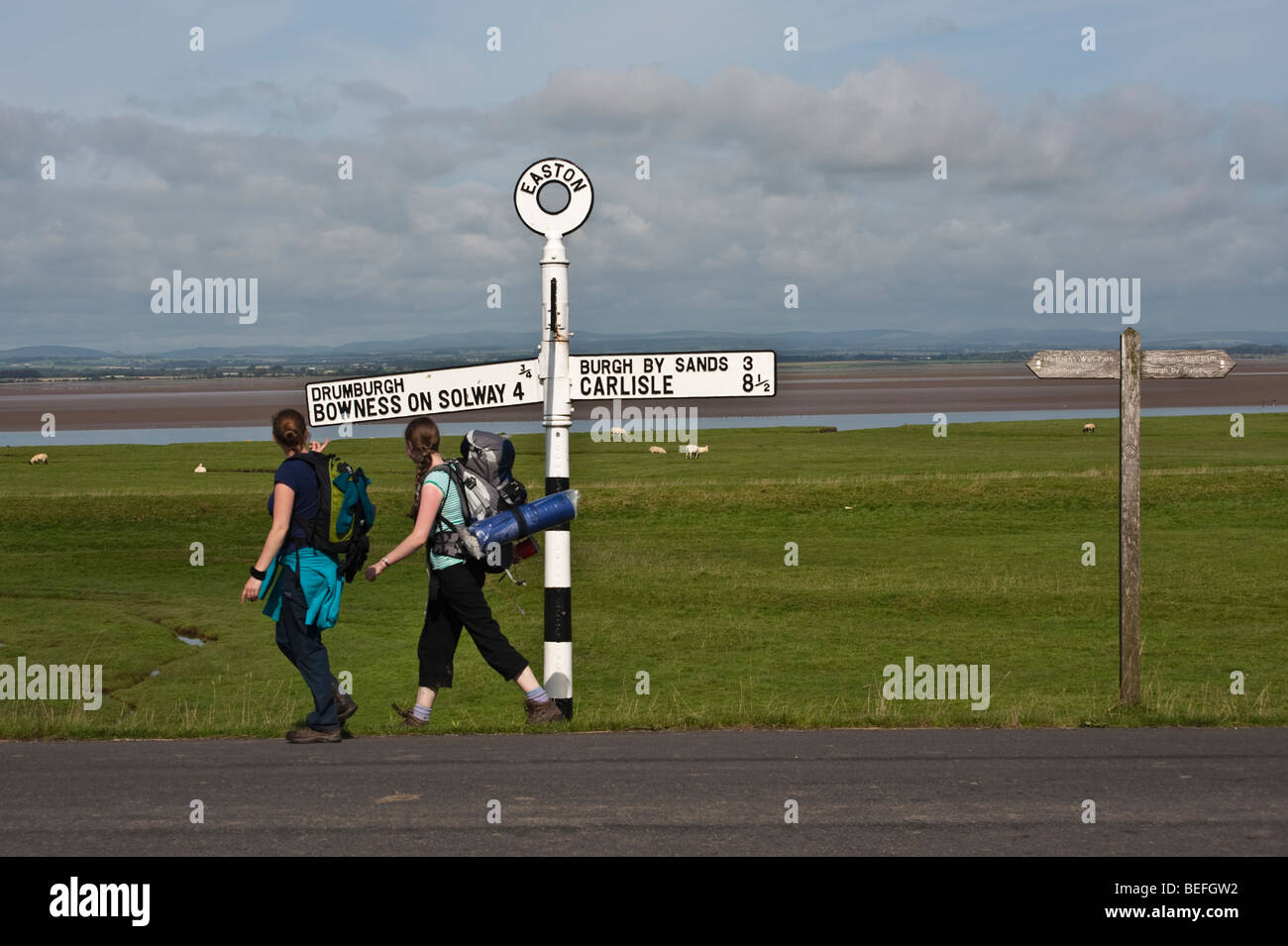 Backpackers completando il vallo di Adriano a lunga distanza sentiero che dura circa 6 giorni, passano i segni a Bowness on Solway, Foto Stock