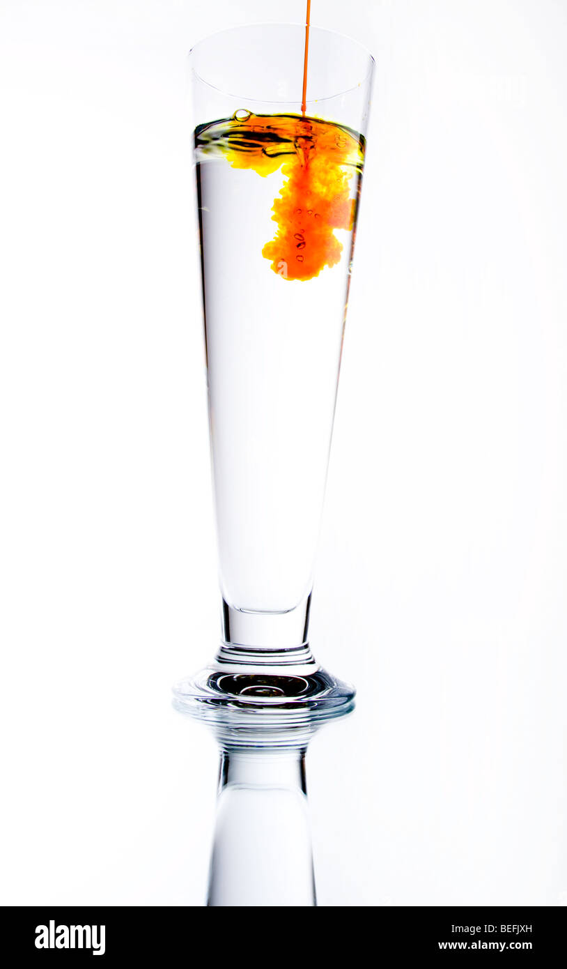Arancione Il liquido viene versato in un liquido trasparente Foto Stock