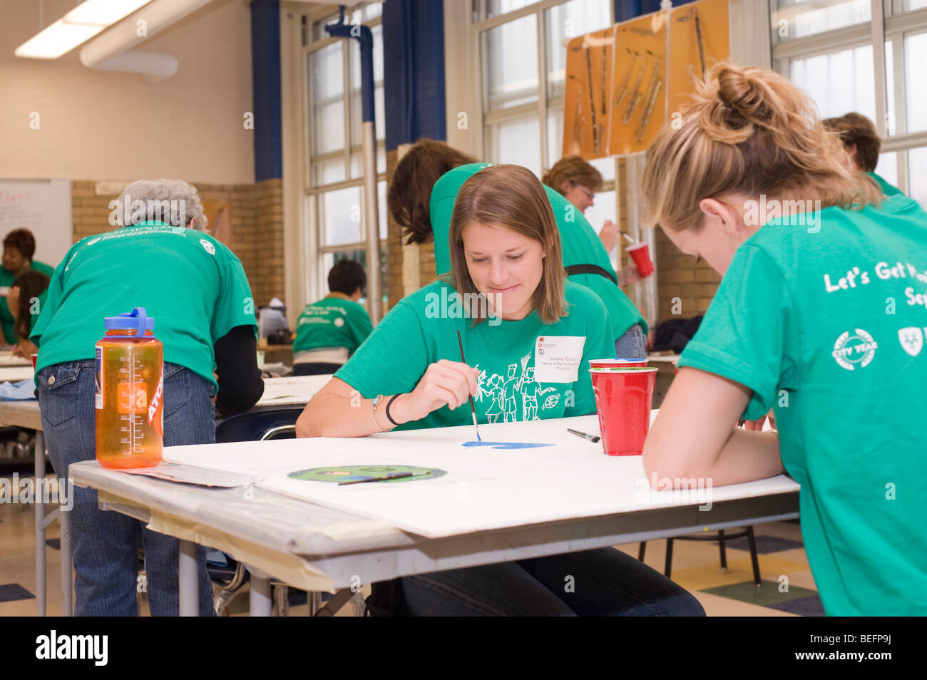 Volontario di Harvard Pilgrim Health Care partecipa in una città anno progetto per ristrutturare una parte interna della città di Boston scuola di charter. Foto Stock