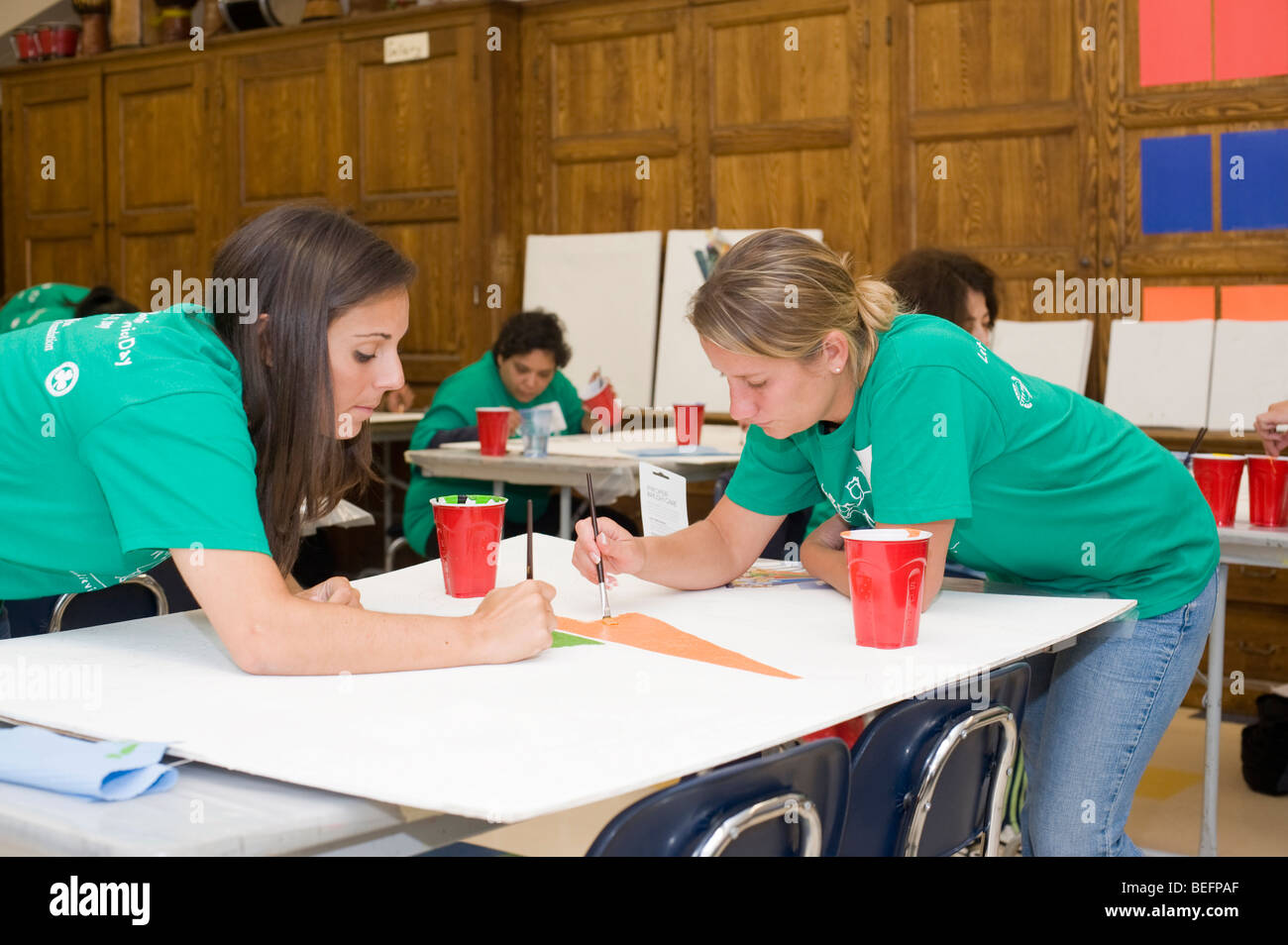 Volontario di Harvard Pilgrim Health Care partecipa in una città anno progetto per ristrutturare una parte interna della città di Boston scuola di charter. Foto Stock