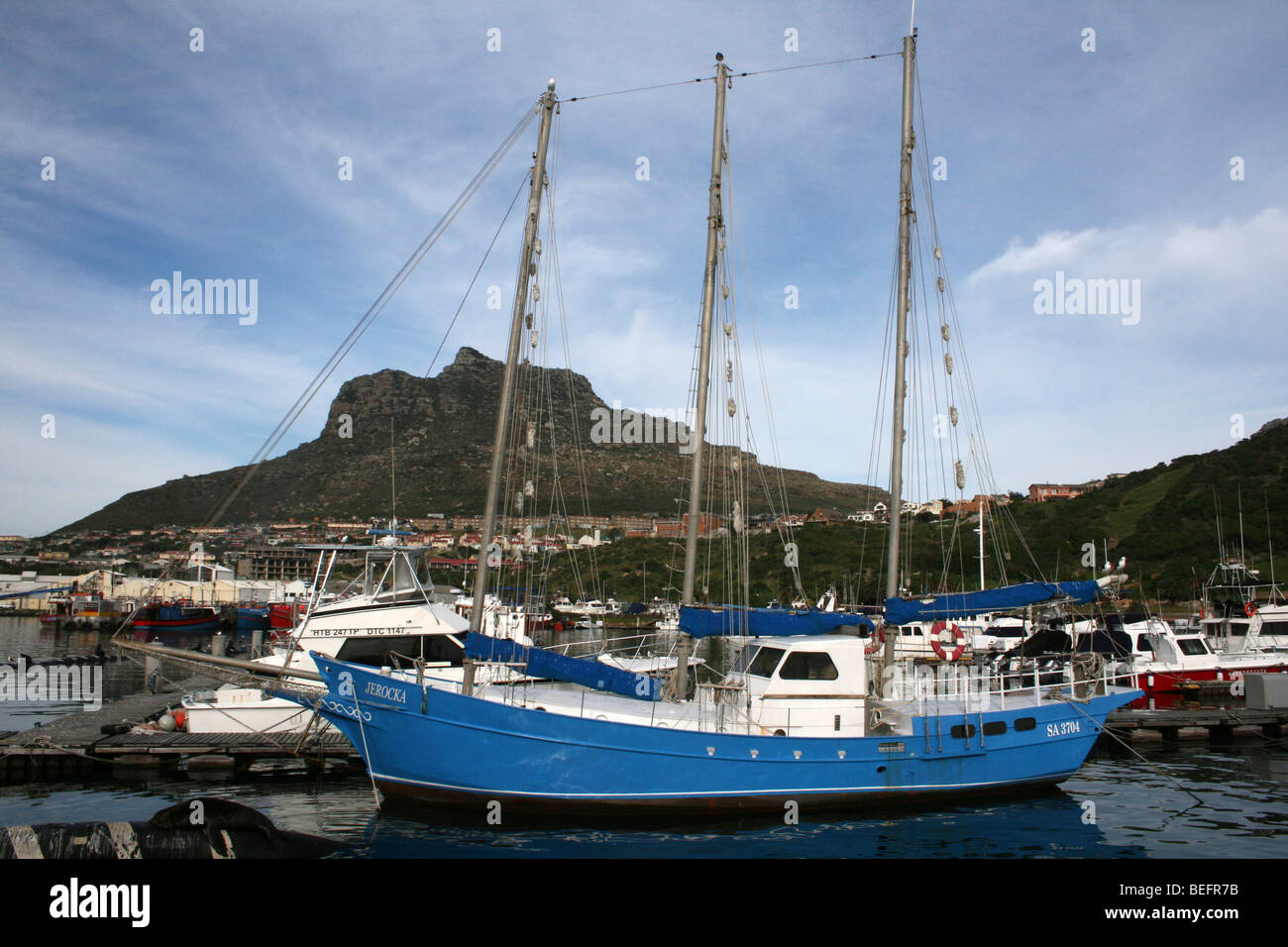 Una barca nel porto di Hout Bay con picco di sentinella nella distanza, Sud Africa Foto Stock
