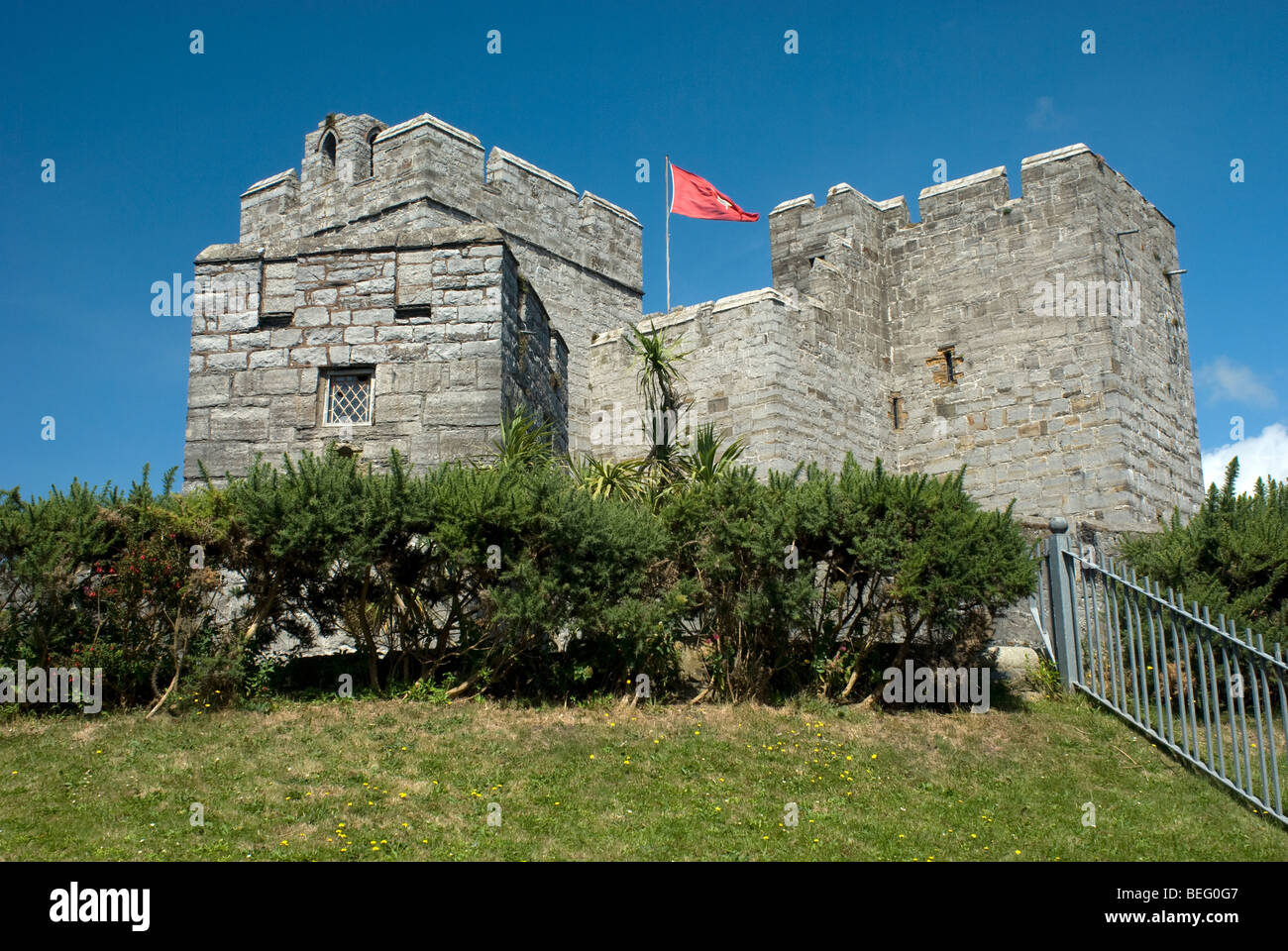 Dettaglio della parte del castello che mostra le merlature e una red flag IOM a Castletown, Isola di Man in una giornata di sole Foto Stock