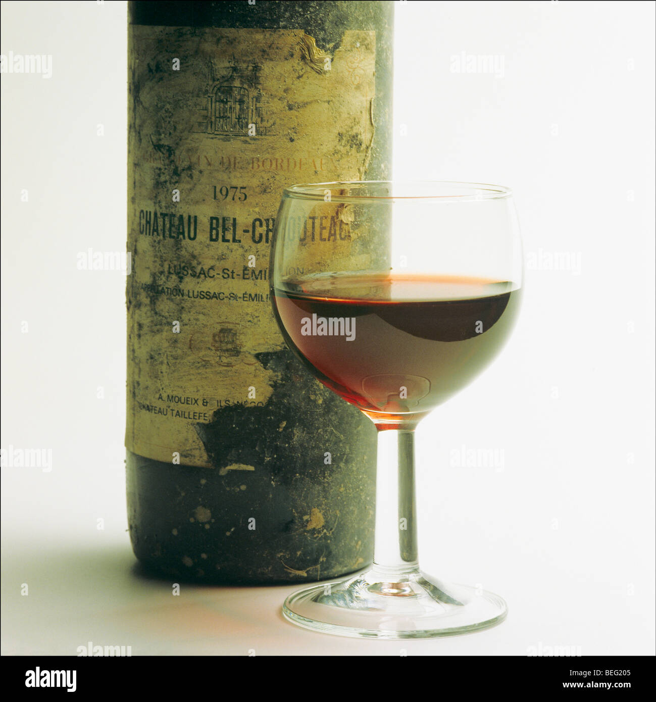 1975 'Chateau Bel-Chouteau' il vino rosso di Bordeaux bottiglia con etichetta danneggiata e wineglass Foto Stock