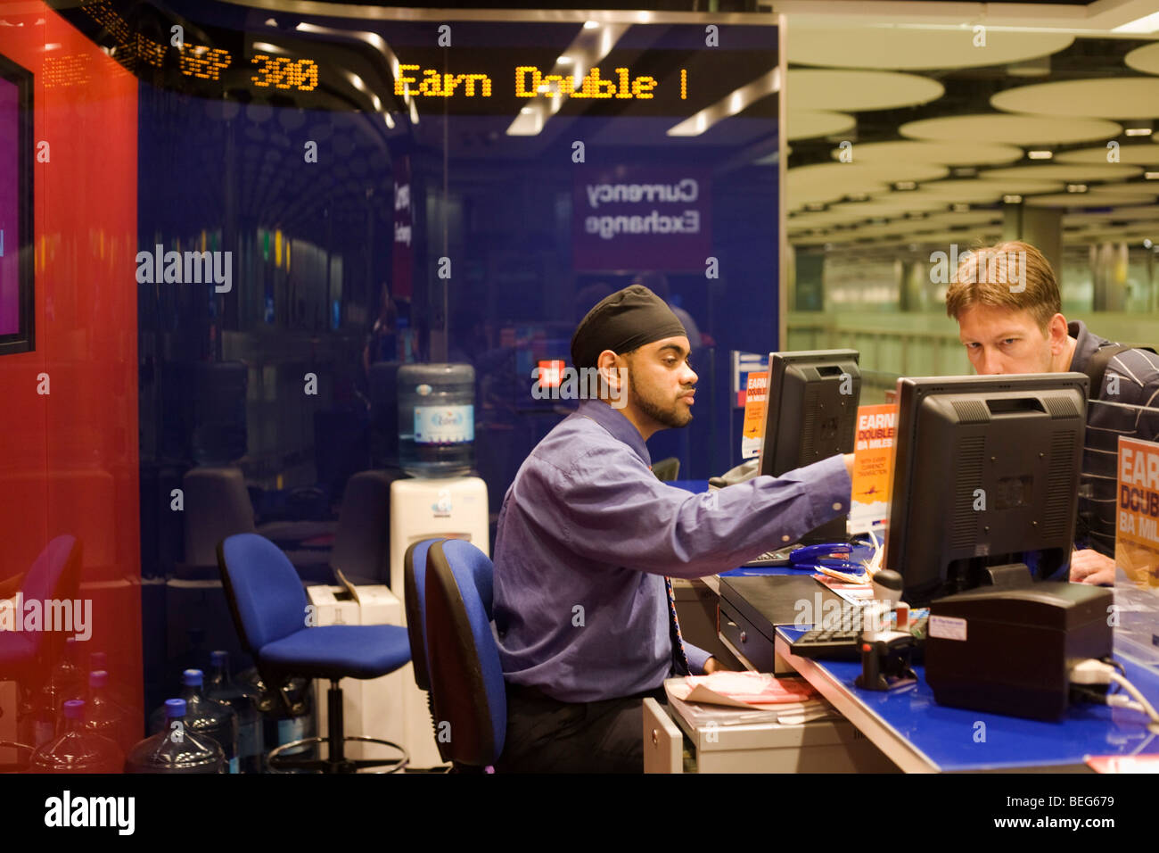 Travelex bureau de change assistant serve valuta per passeggero in aeroporto di Heathrow il terminal 5 Foto Stock