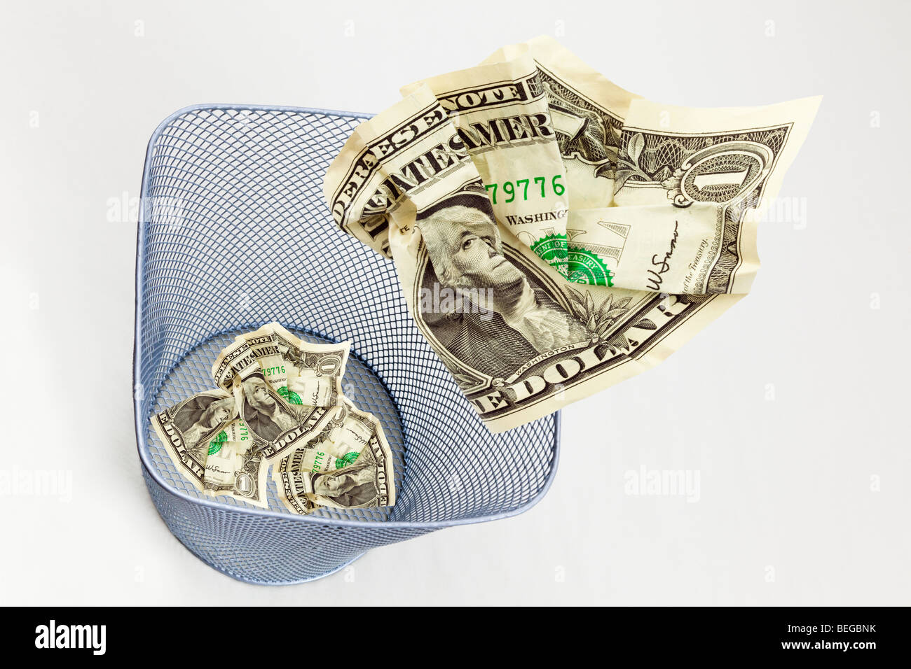 Immagine composita della US Dollar Bills dollari gettati in un cestino per carta su sfondo semplice dal di sopra per illustrare USA sprecare denaro concept Foto Stock