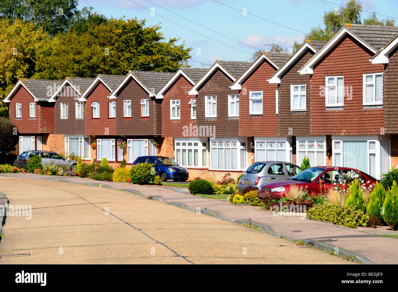 Fila di case in via residenziale di case immobiliari proprietà di sviluppo identico case indipendenti giardini individuali e vialetto auto Inghilterra Regno Unito Foto Stock