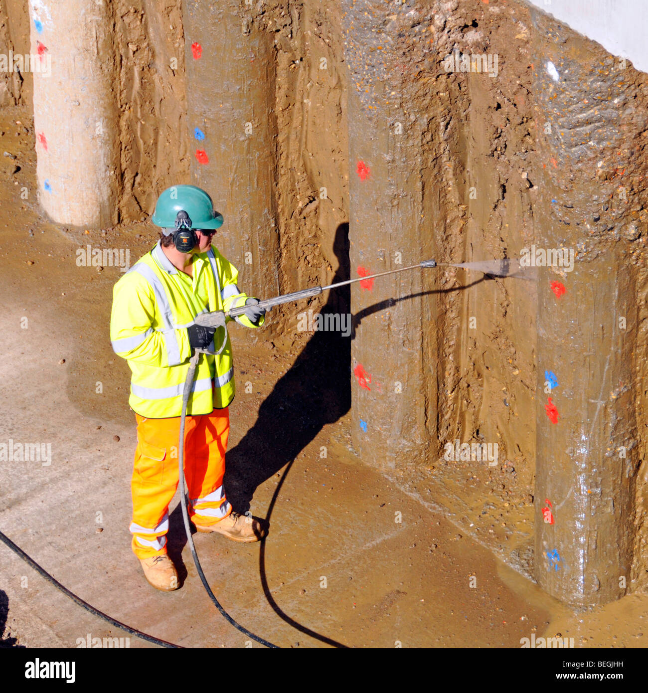 Parete di ritegno sull'acqua ad alta pressione del lavoratore del cantiere edile Spruzzare argilla pulita da nuove pile di calcestruzzo M25 allargamento dell'autostrada Essex Inghilterra Regno Unito Foto Stock