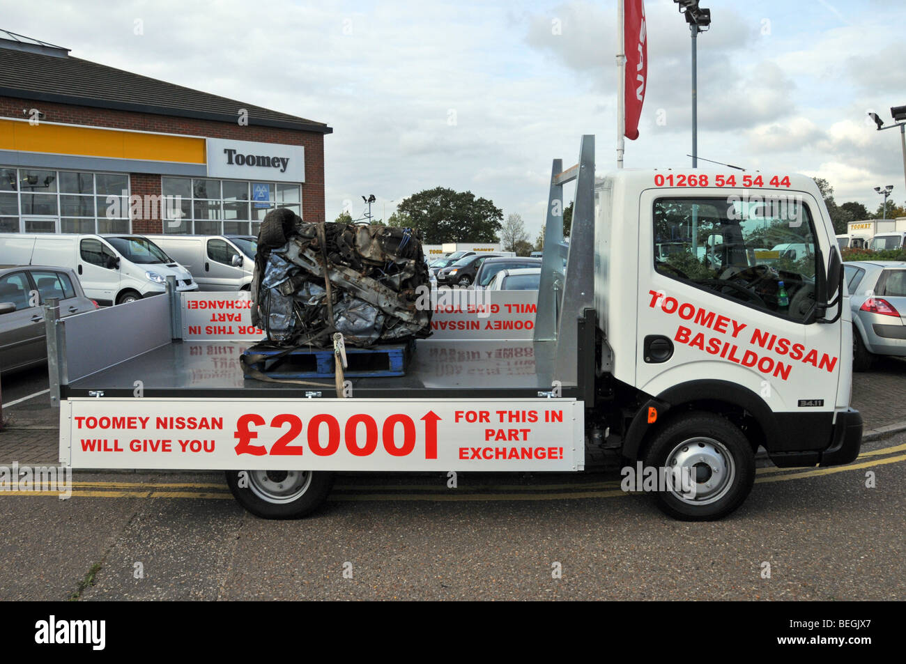 Nissan auto concessionario pick-up camion che trasporta una vecchia auto schiacciata come promozione per il governo auto scrappage schema Essex concessionaria Inghilterra UK Foto Stock