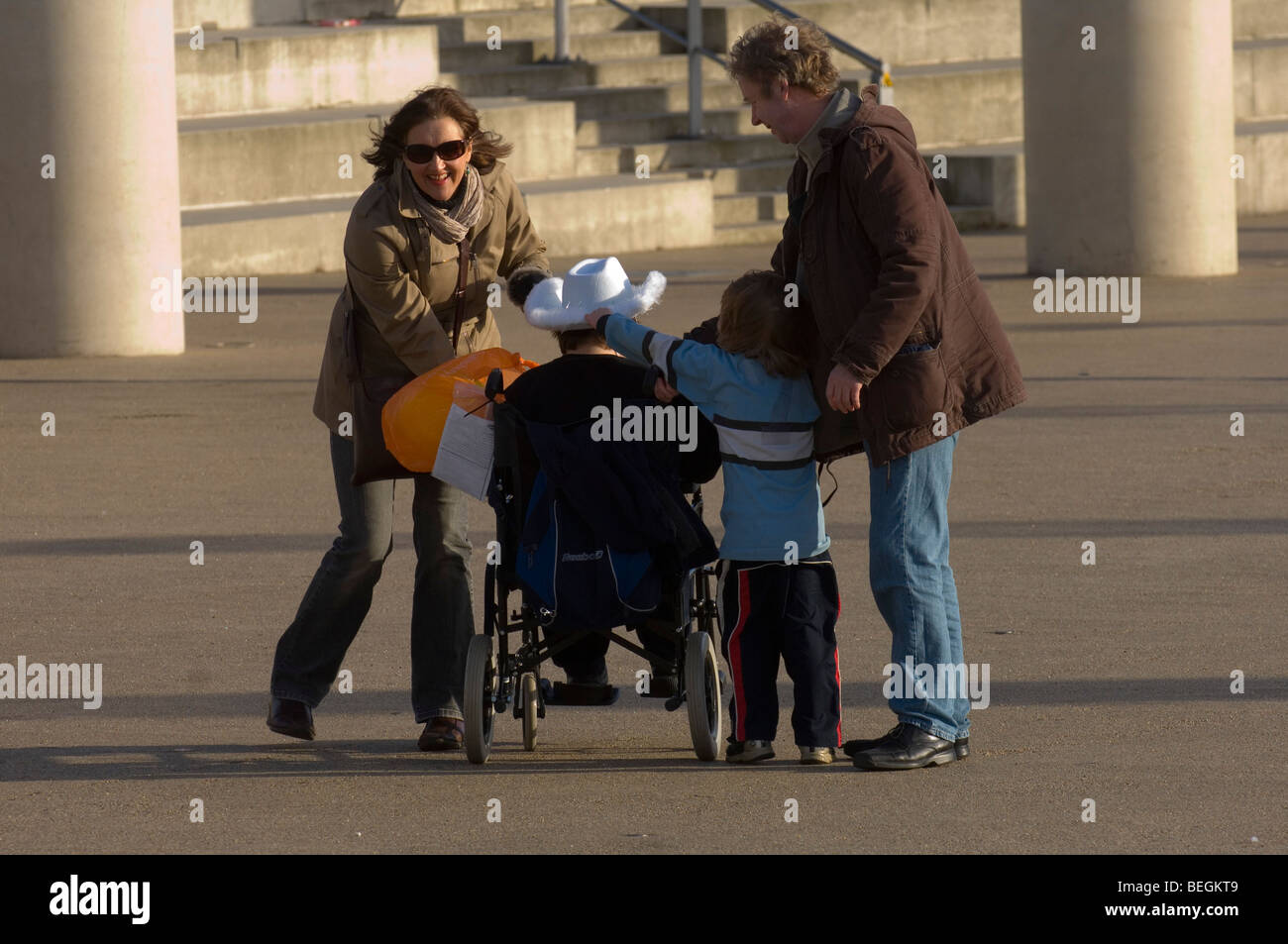Coppia con persone disabili in sedia a rotelle presso la Baia di Cardiff, Cardiff, Galles, Regno Unito. Foto Stock