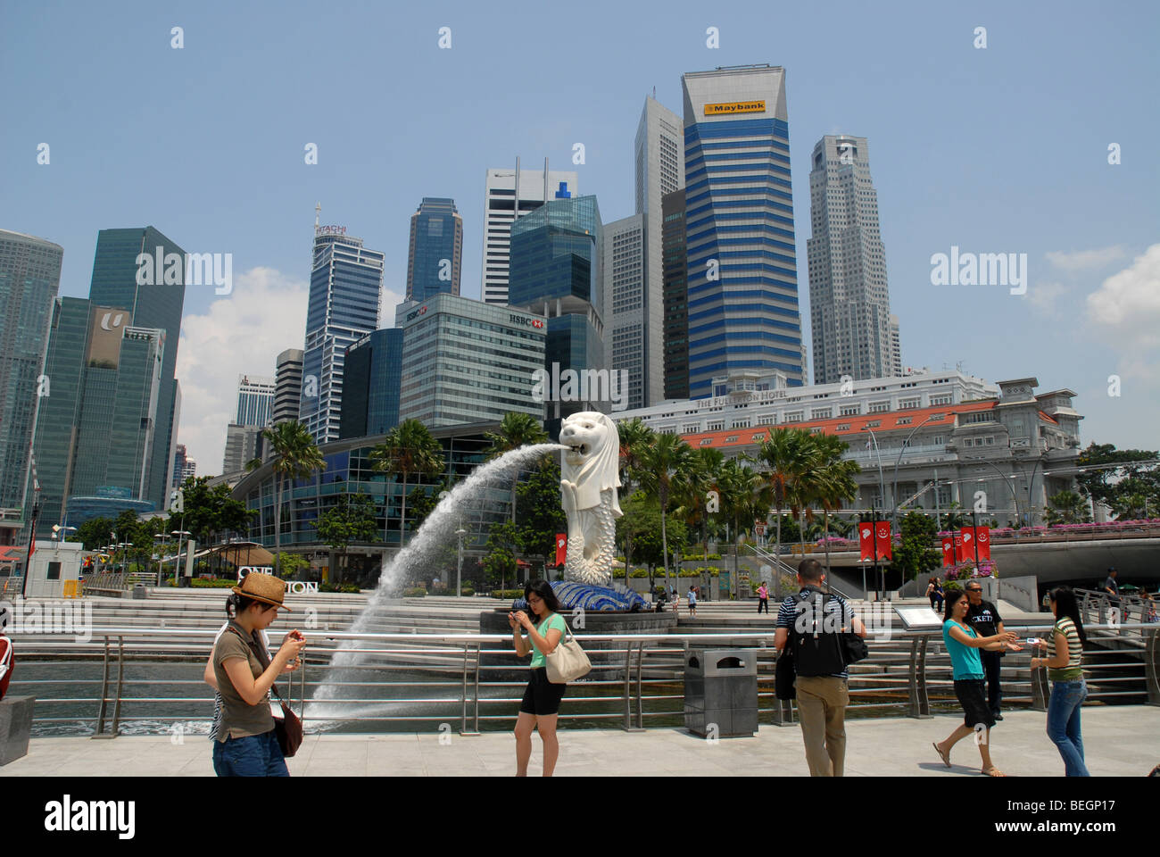 I turisti scattano fotografie di fronte al Merlion e dello skyline della città, Singapore Foto Stock