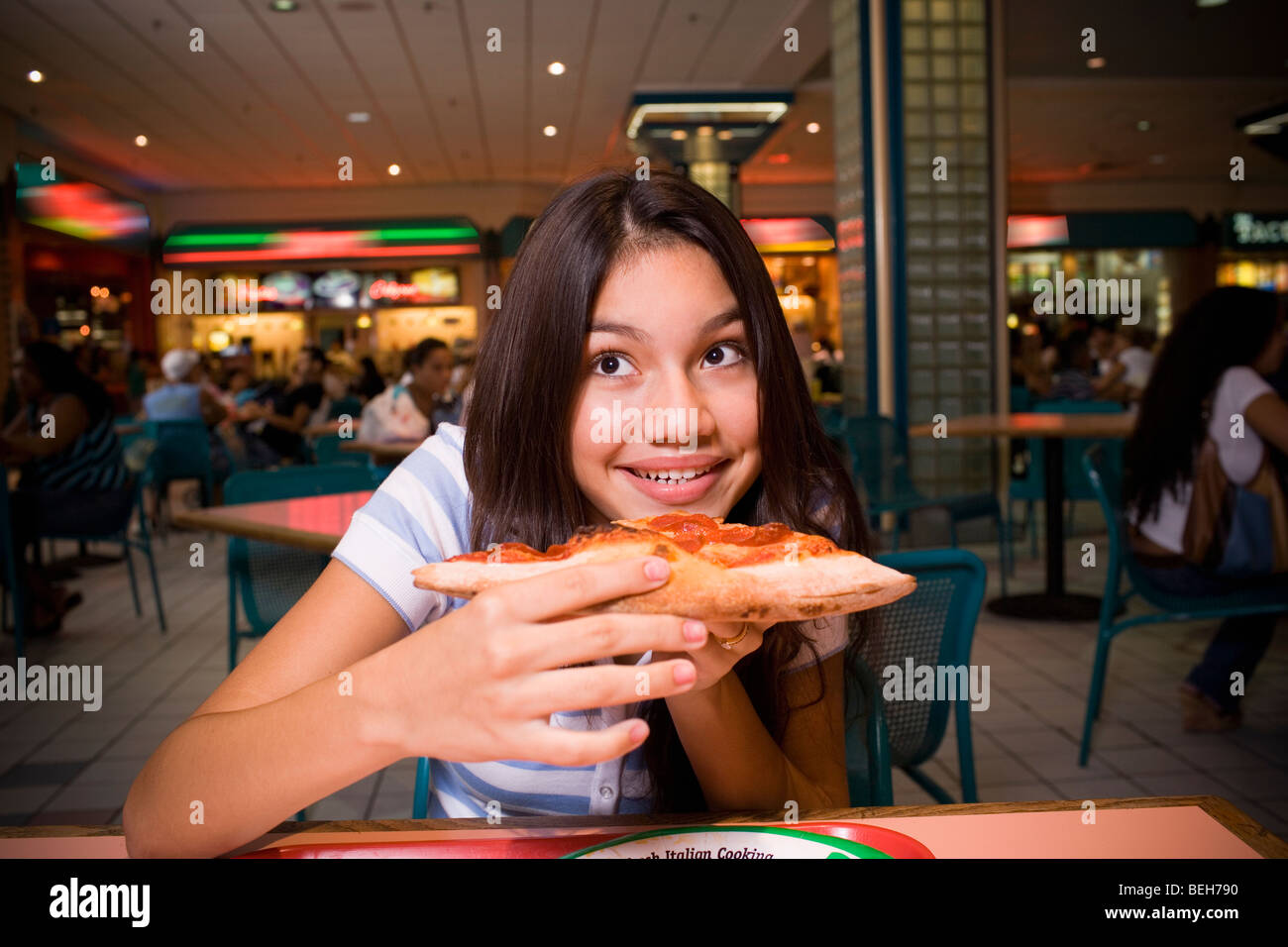 Ragazza adolescente di mangiare la pizza in mall food court Foto Stock