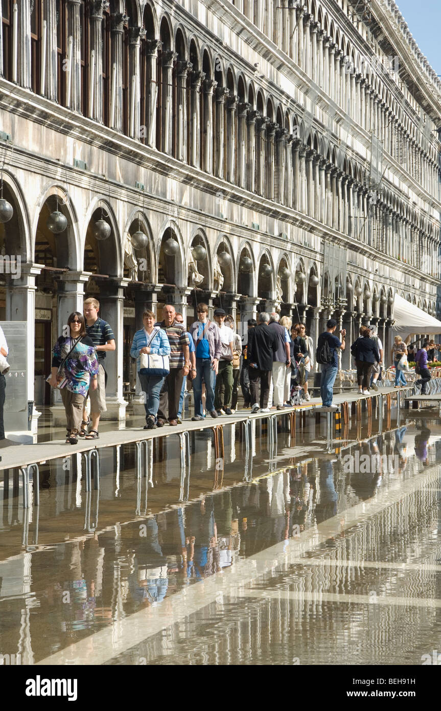 La gente che camminava sul duckboards sollevata in piazza San Marco Venezia dopo un allagamento Foto Stock