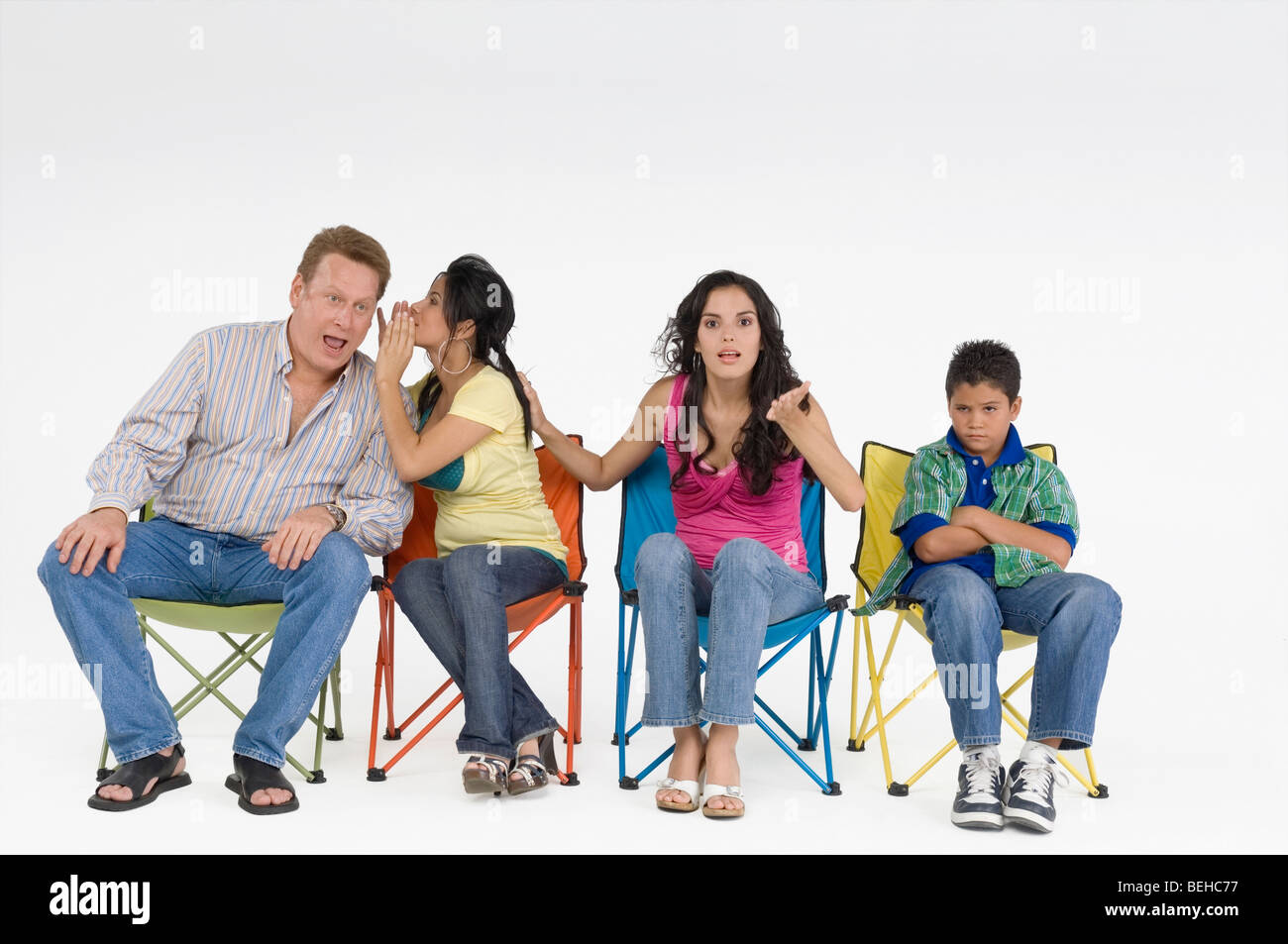 Uomo maturo con i suoi tre bambini seduti su sedie Foto Stock